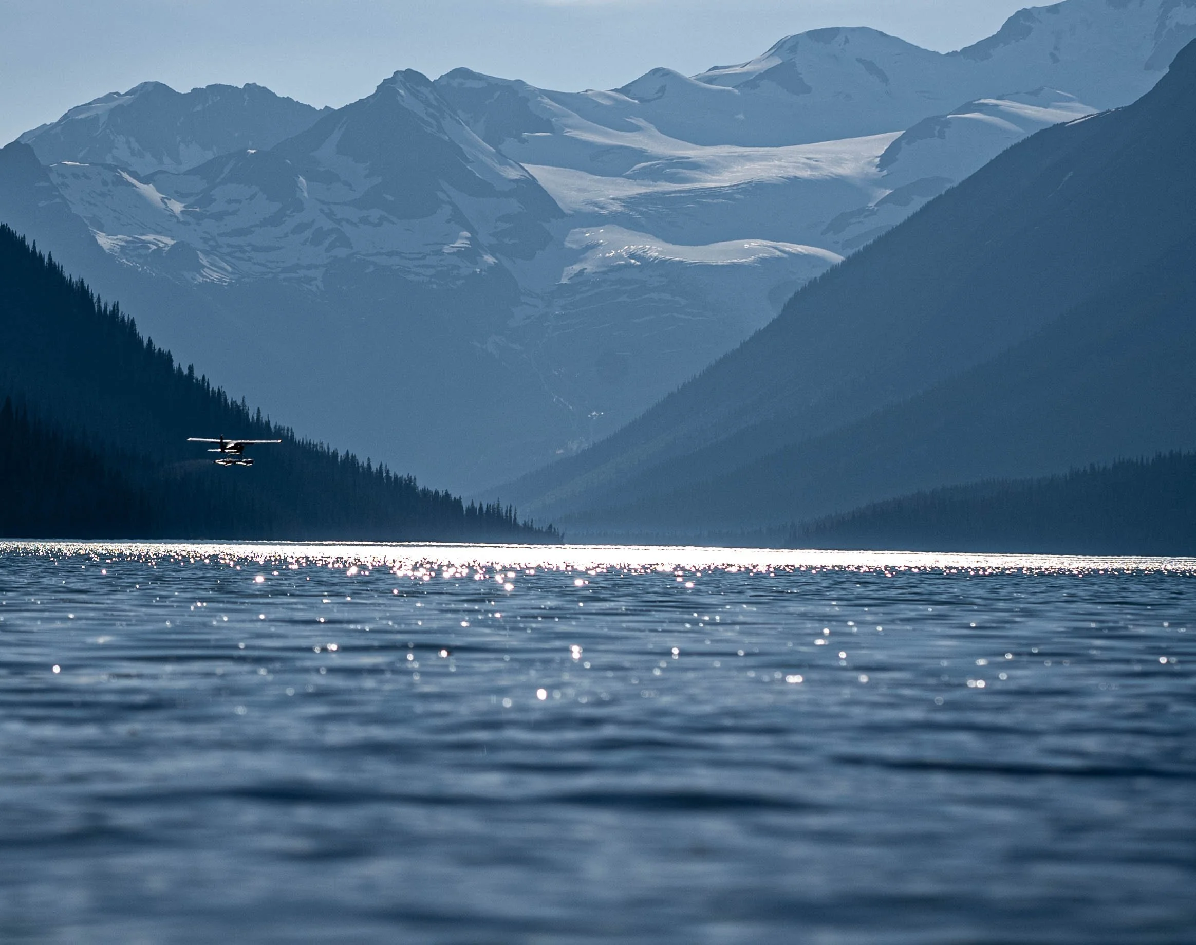 float plane flying over lake with mountain views