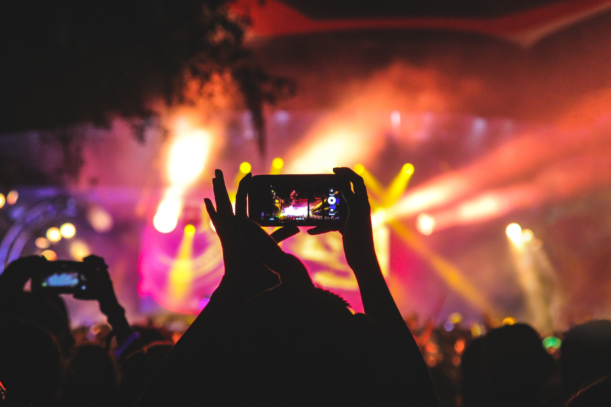 Person holding smartphone to record concert at night