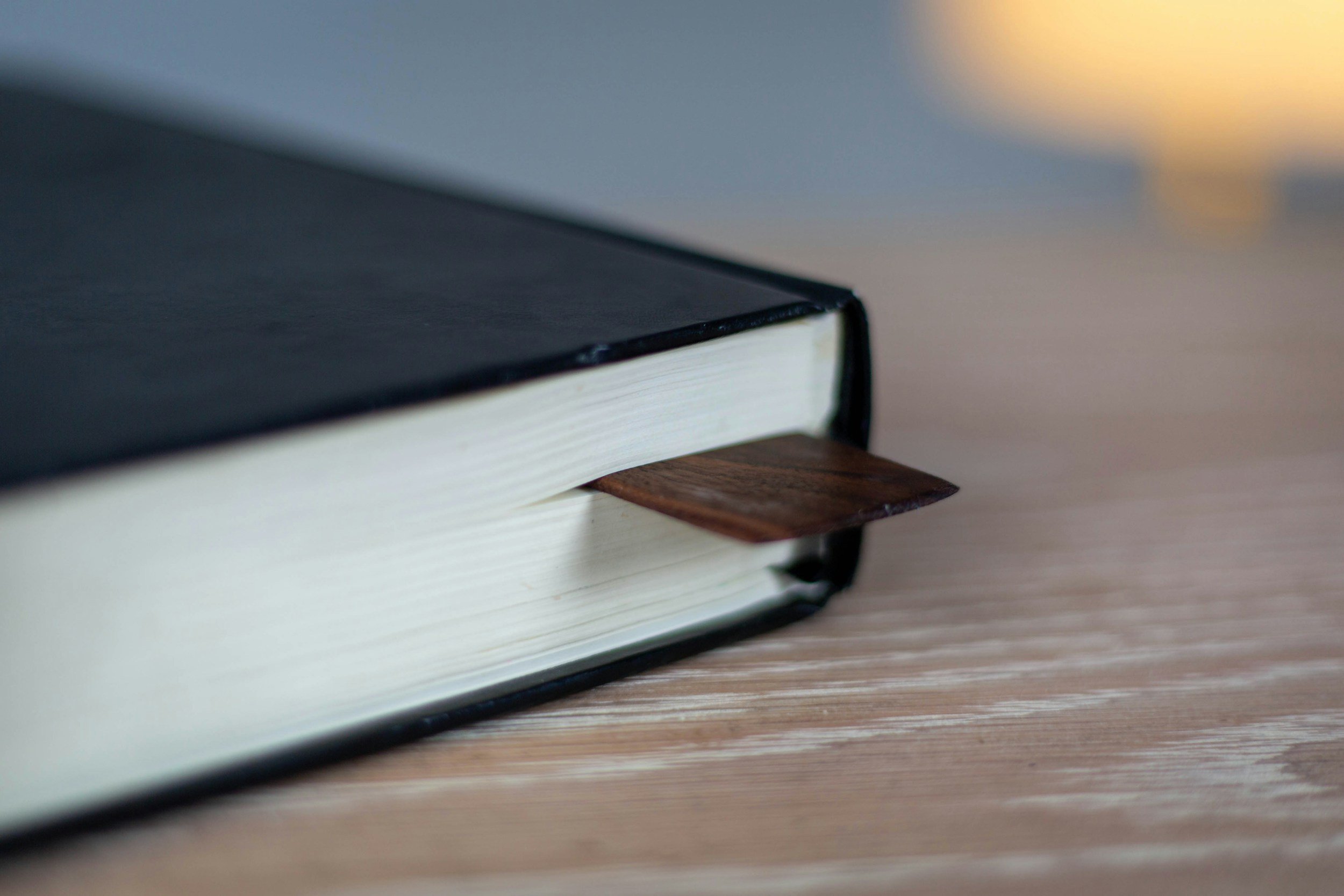 Close-up of a stack of open books with cream pages, viewed from the side on a flat surface.