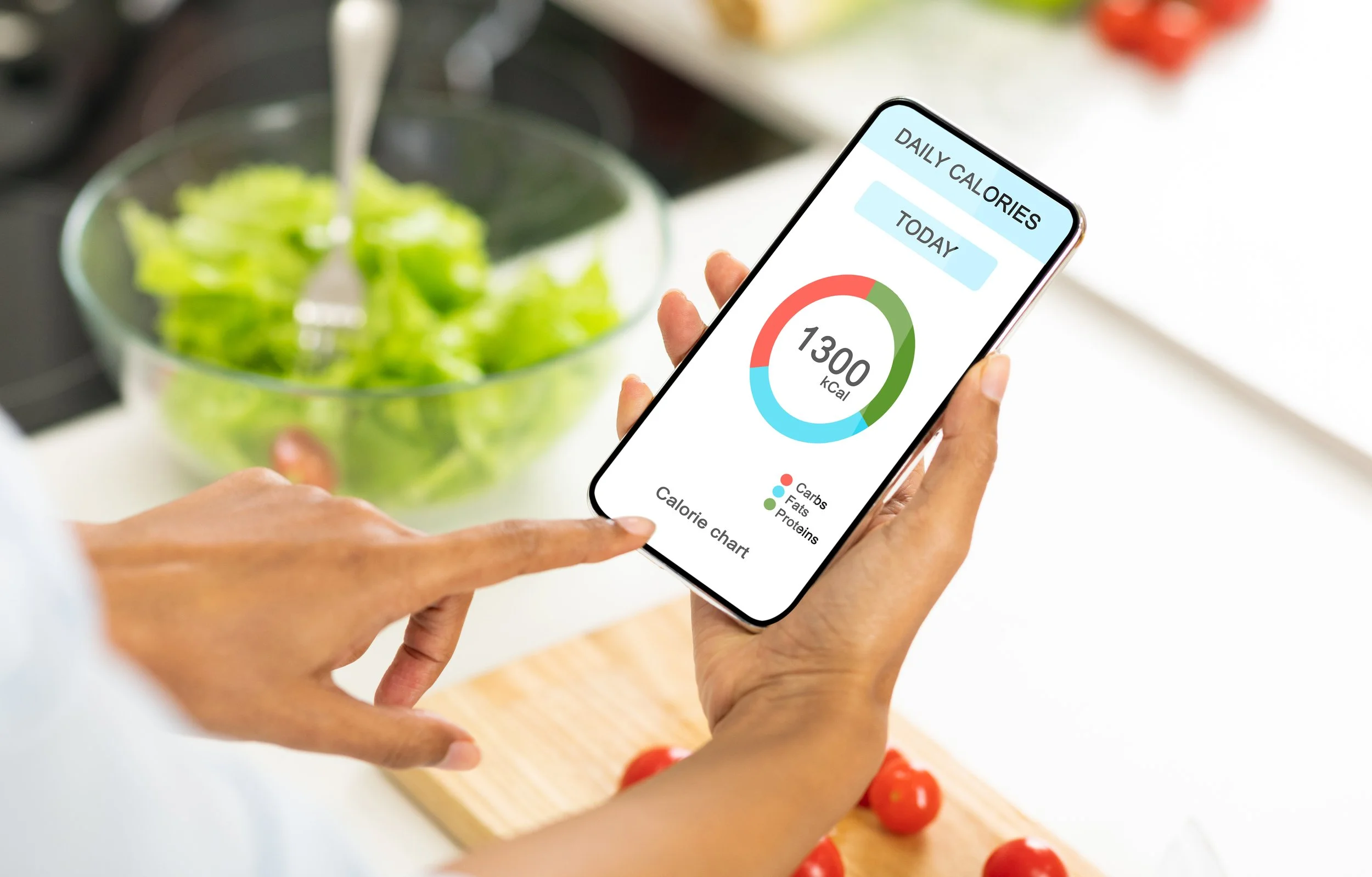 Photo of a woman's hand holding her phone with a calorie-counting app on the screen.