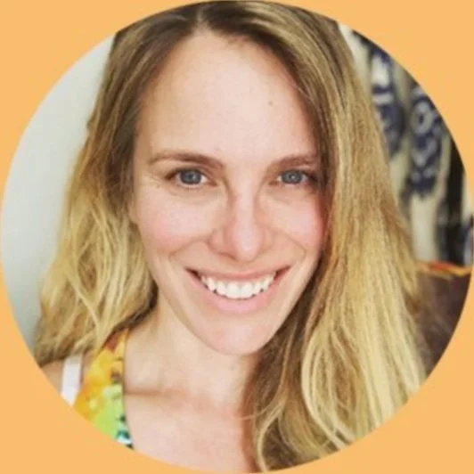 A young woman with long blonde hair and a bright smile, wearing a colorful top, in front of an orange background.