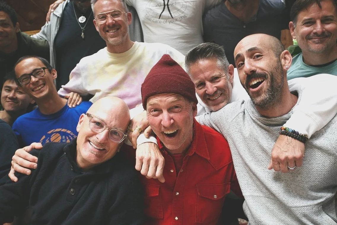 A group of people smiling and hugging each other at a social gathering.