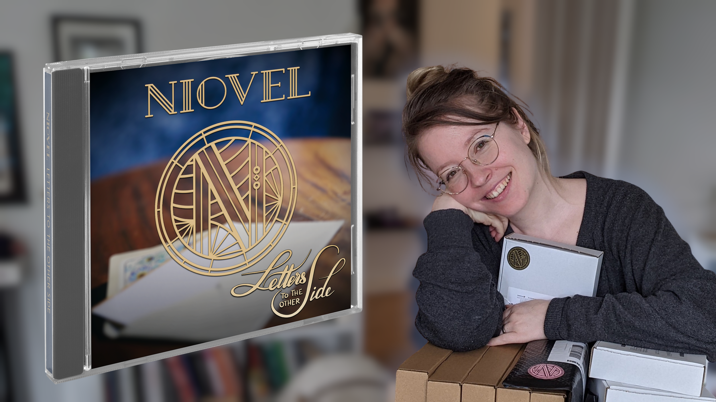 A woman with glasses and a black sweater smiling as she leans on her hand, sitting at a table with several boxes and a book or box in front of her. There is a CD case with cover art titled 'Letters to the Other Side' standing on the table, featuring a dark blue background, stylized gold circular logo, and the words 'Novel' and 'Letters to the Other Side'.