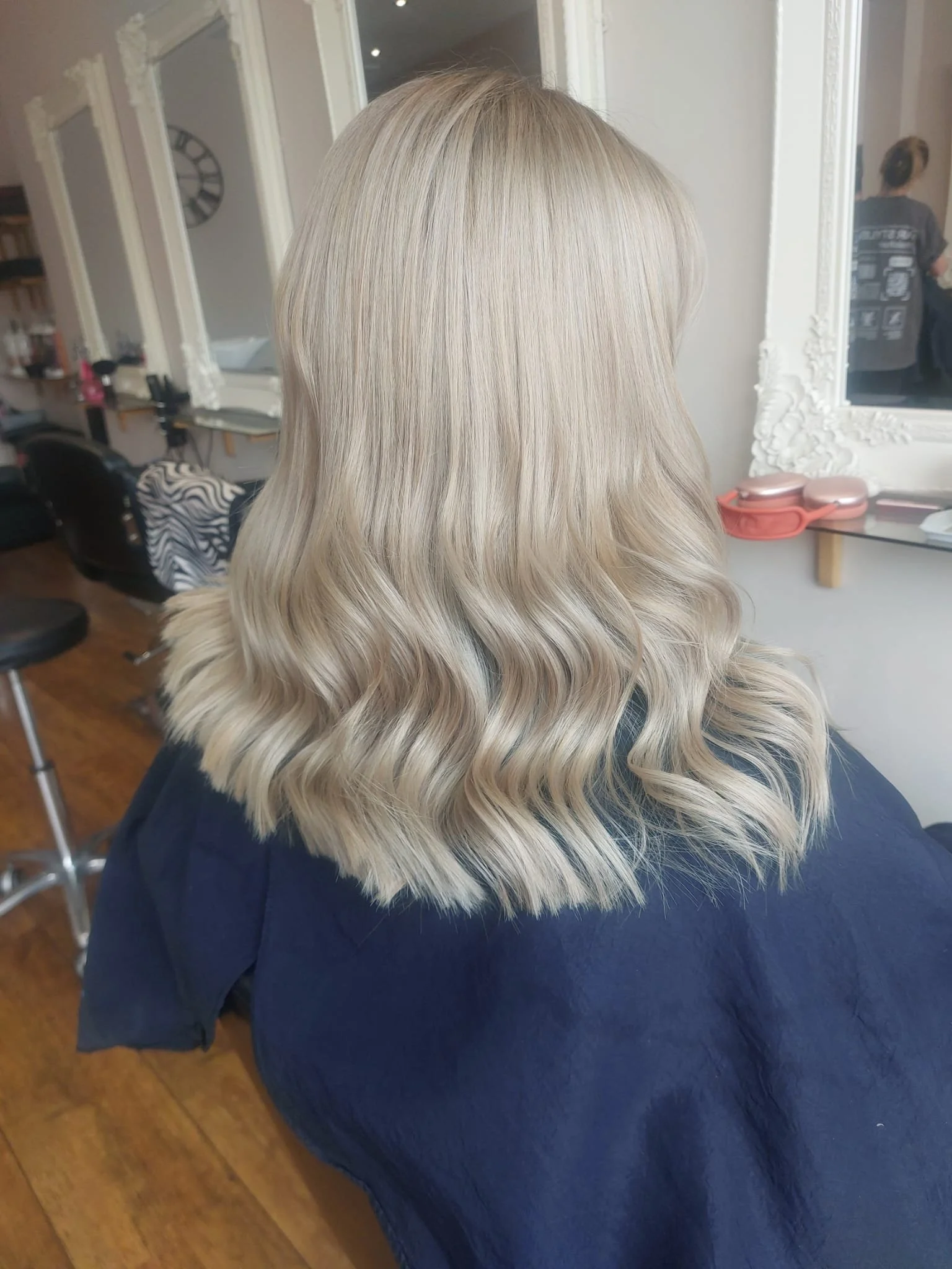 Back of a woman with shoulder-length, wavy blonde hair sitting in a hair salon.