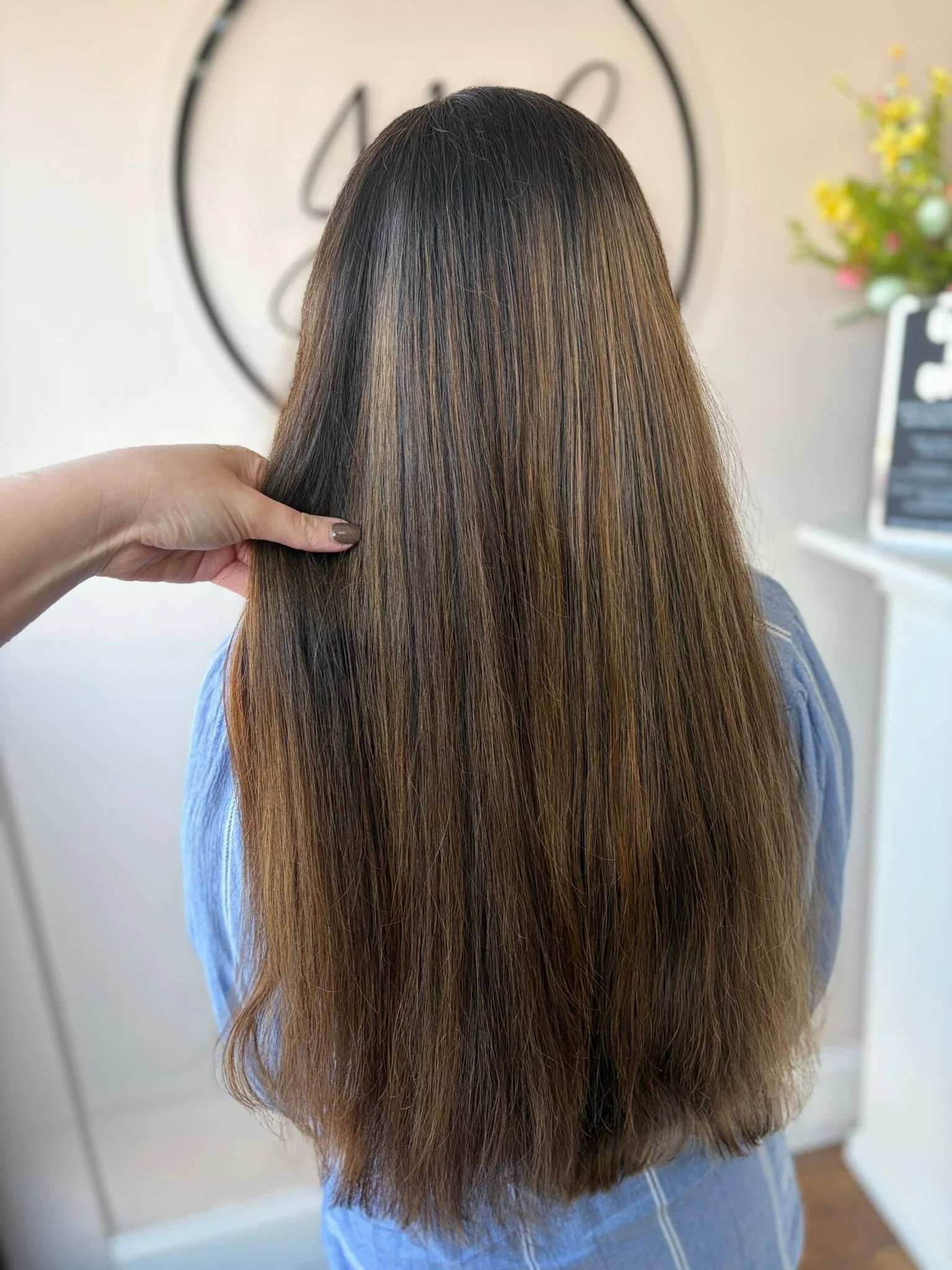 Back of a woman with long, straight, brown hair.