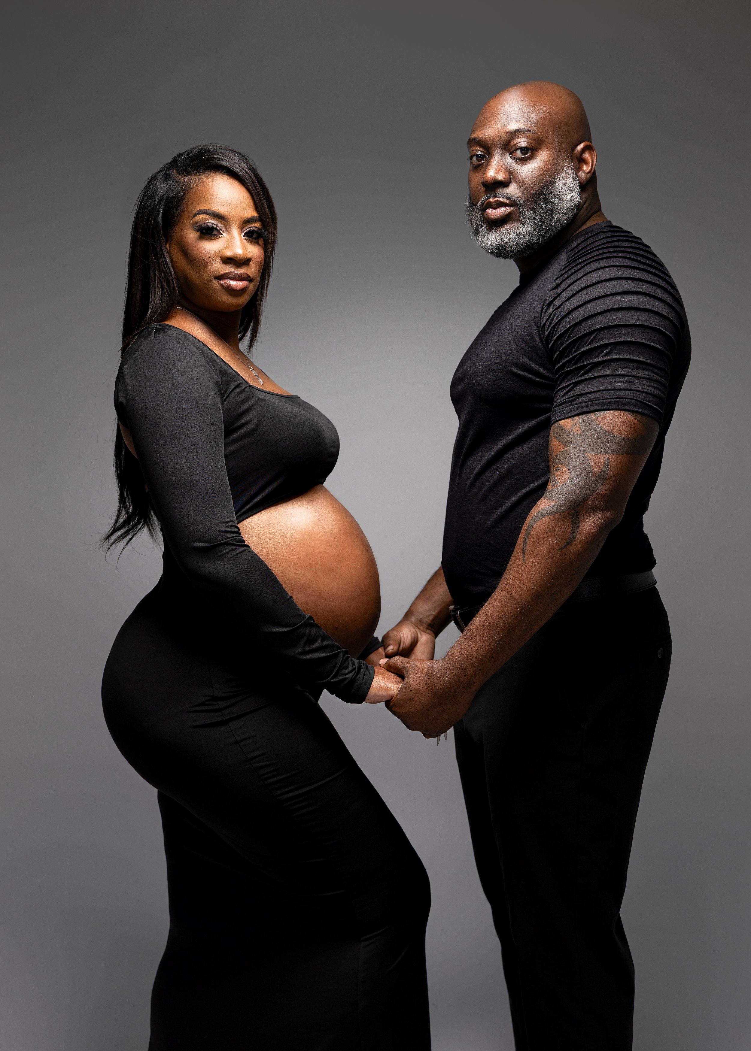 couple maternity photo of parents to be holding hands and looking into the camera