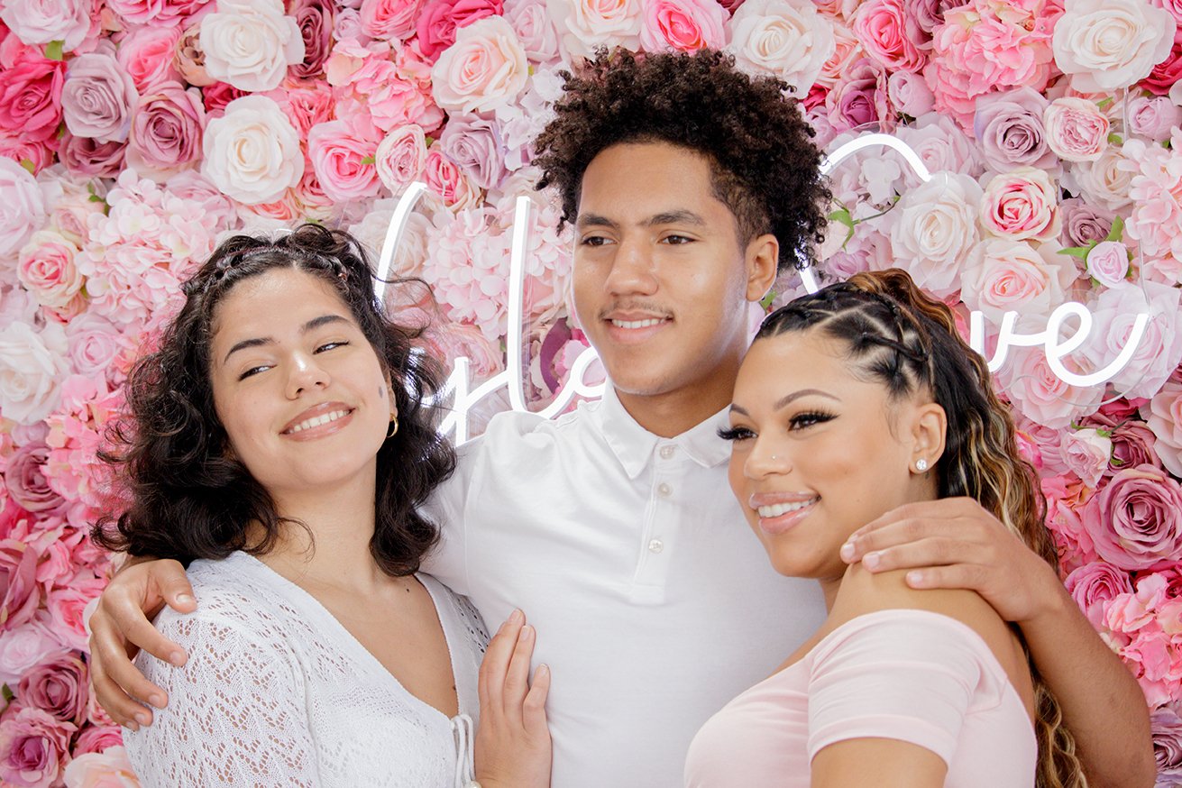baby shower event photography of 3 people smiling in front of a flower wall