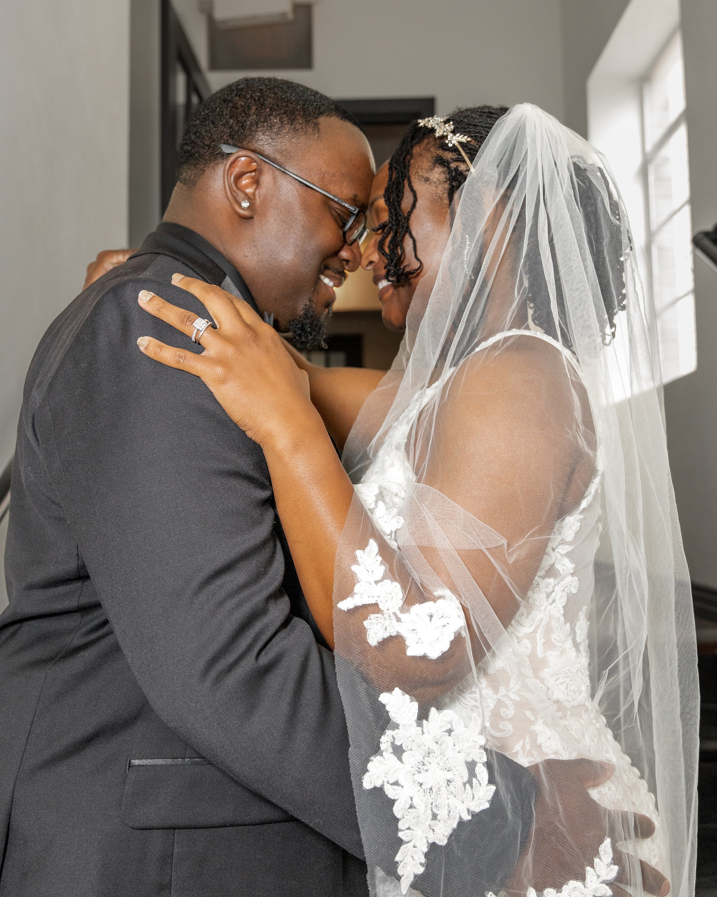 A joyful bride and groom embracing each other, smiling, with their foreheads touching, during their wedding.