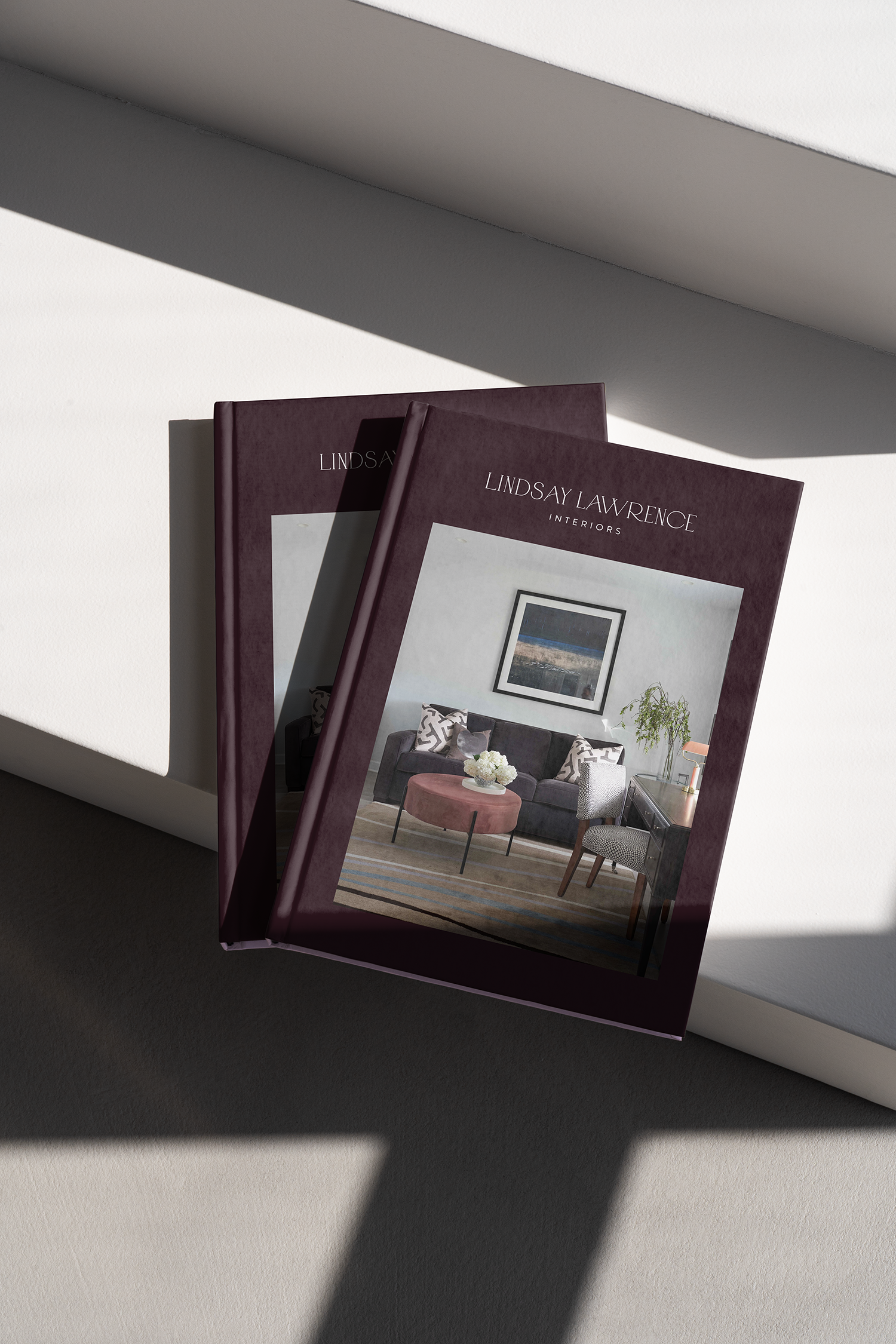 Magazine titled "Lindsay Lawrence Interiors" showing a living room interior with a sofa, chairs, and artwork, viewed on a white surface with shadows.