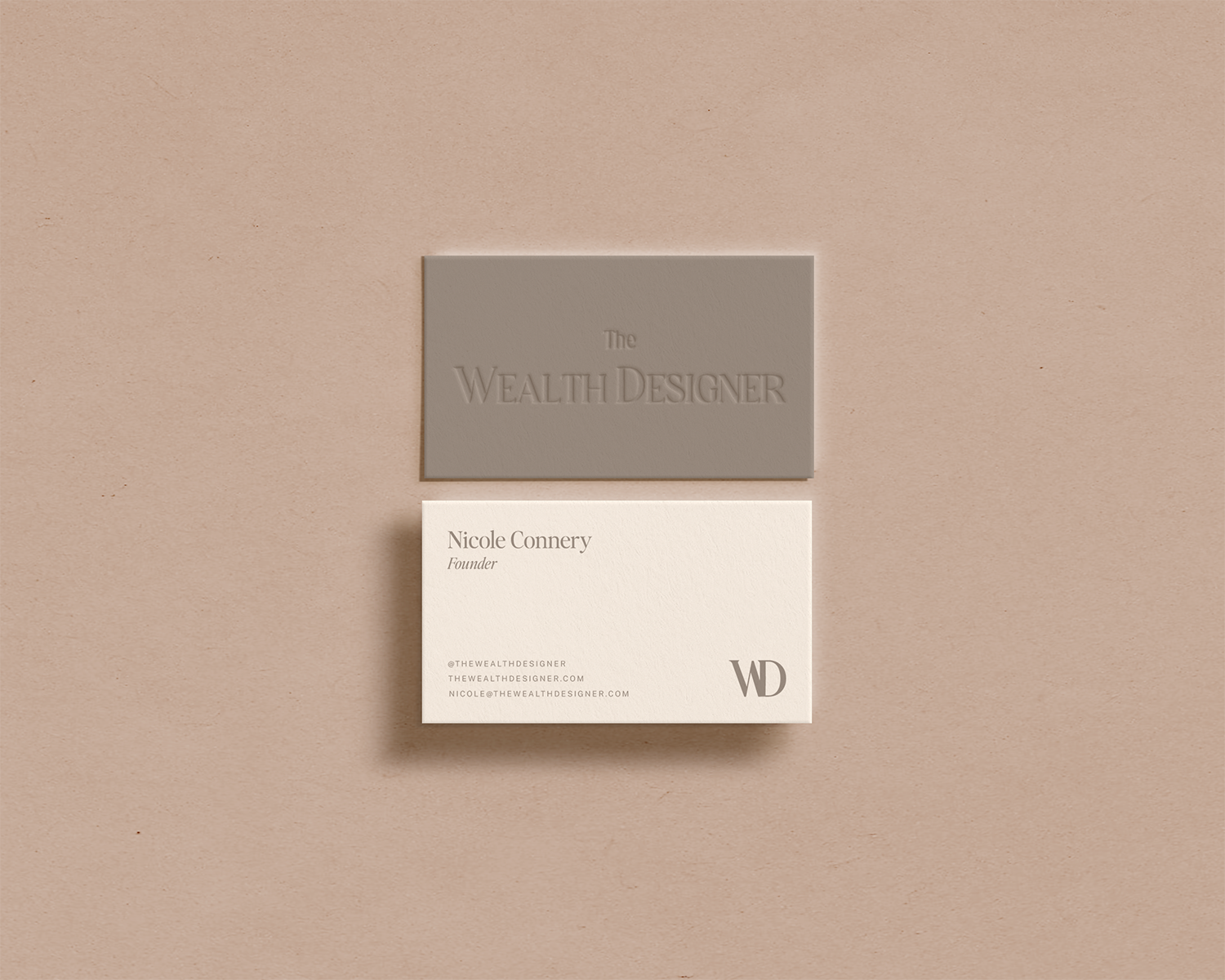 Business cards on a beige background, one gray with embossed text 'The Wealth Designer,' and one white with text 'Nicole Conery, Founder, and contact details including email and website.