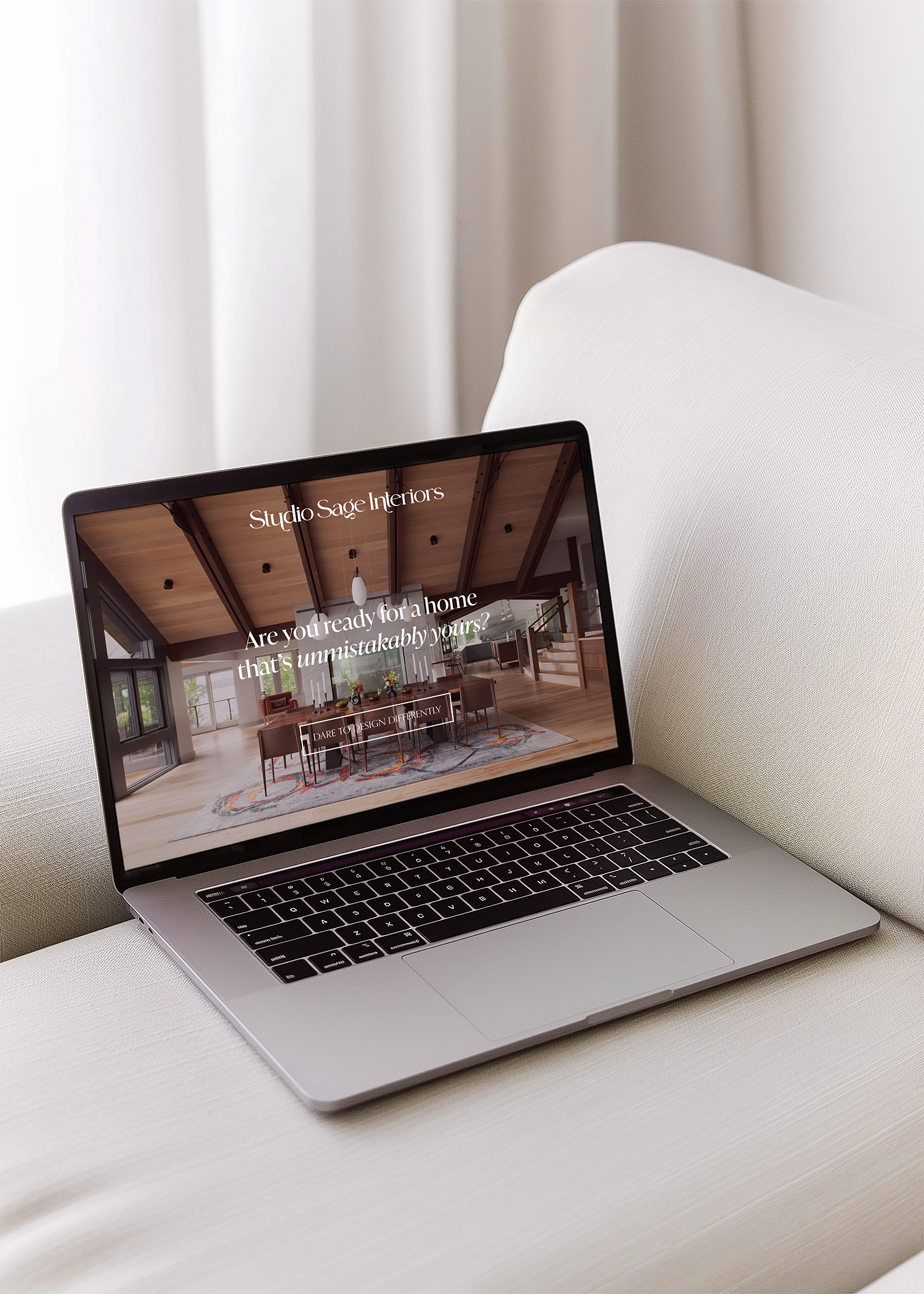 A laptop displaying the website Studio Sage Interiors on a white surface with a white curtain in the background.