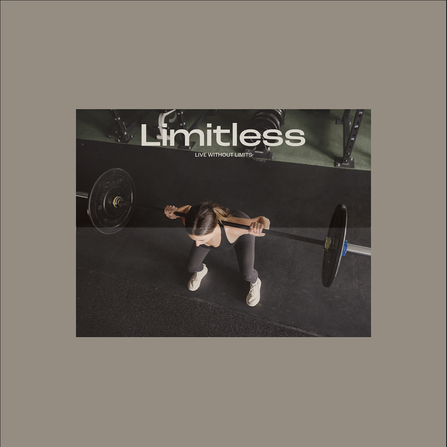 A woman lifting a barbell in a gym with black flooring and fitness equipment in the background.