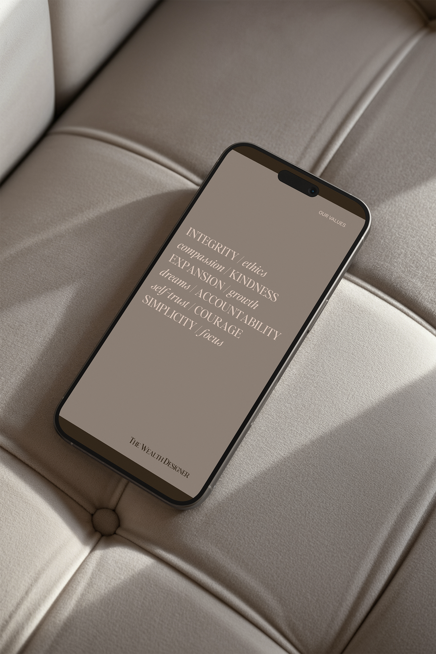 Close-up of a smartphone resting on a beige, cushioned surface, displaying text about integrity, values, and wealth design.