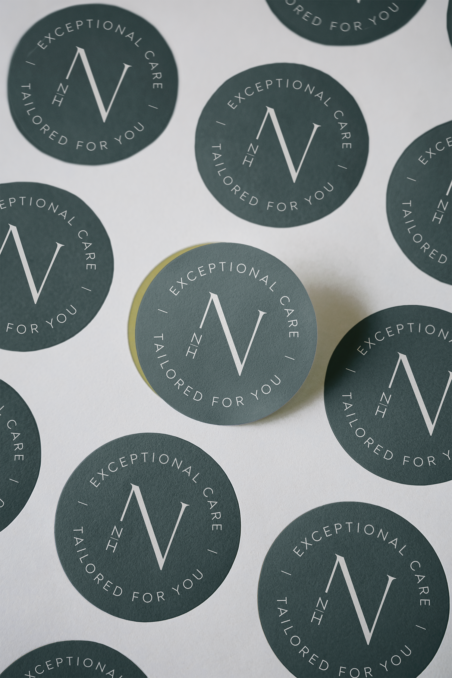 Close-up view of round stickers with the message "Exceptional Care, Tailored for You" surrounding a large letter 'V' in the center.