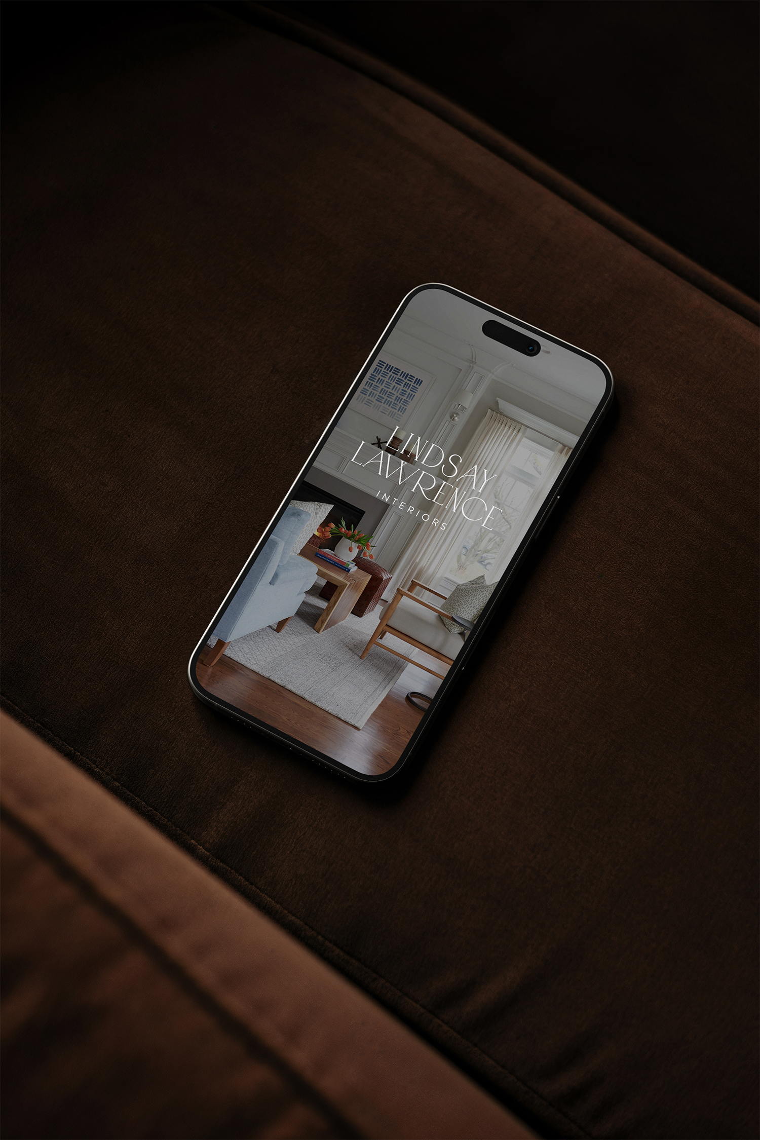 Smartphone displaying an interior design website called Lindsay Lawrence Interiors with a living room image and text overlay.