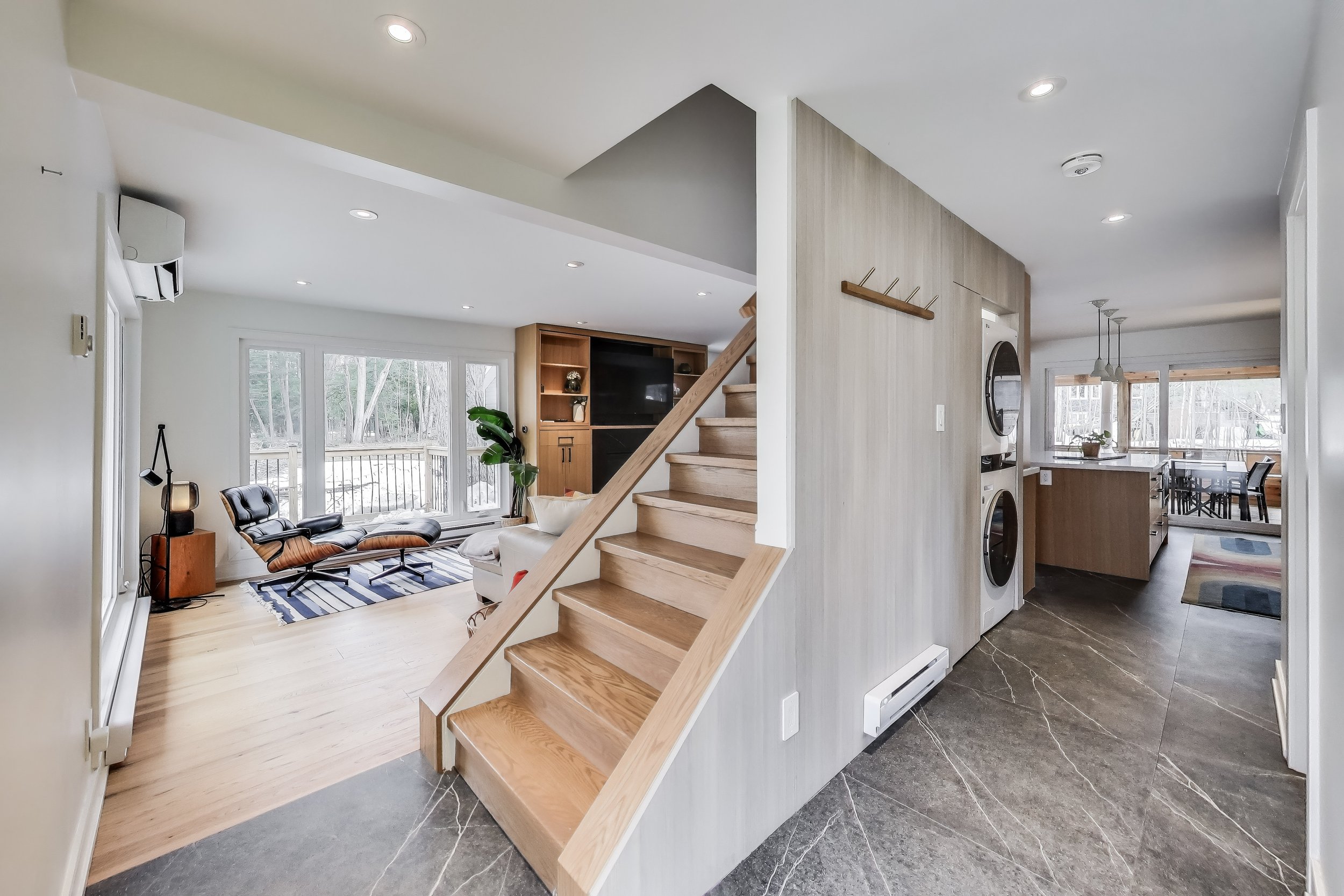 Renovated living room in Muskoka A-frame cottage featuring modern furnishings, large windows with lake views, and a cozy, open-concept design — perfect for relaxing and enjoying family time in Ontario's cottage country.