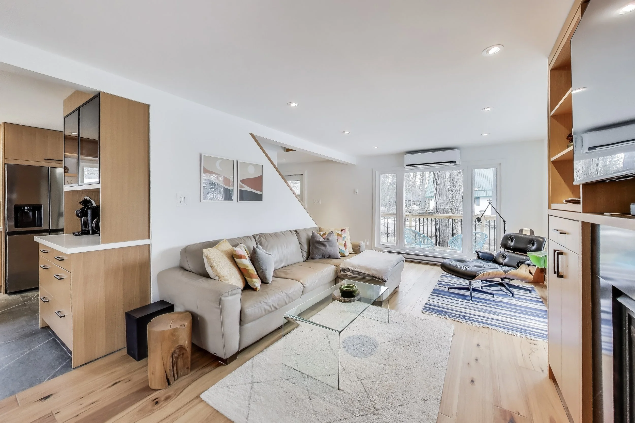 Renovated living room in Muskoka A-frame cottage featuring modern furnishings, large windows with lake views, and a cozy, open-concept design — perfect for relaxing and enjoying family time in Ontario's cottage country.