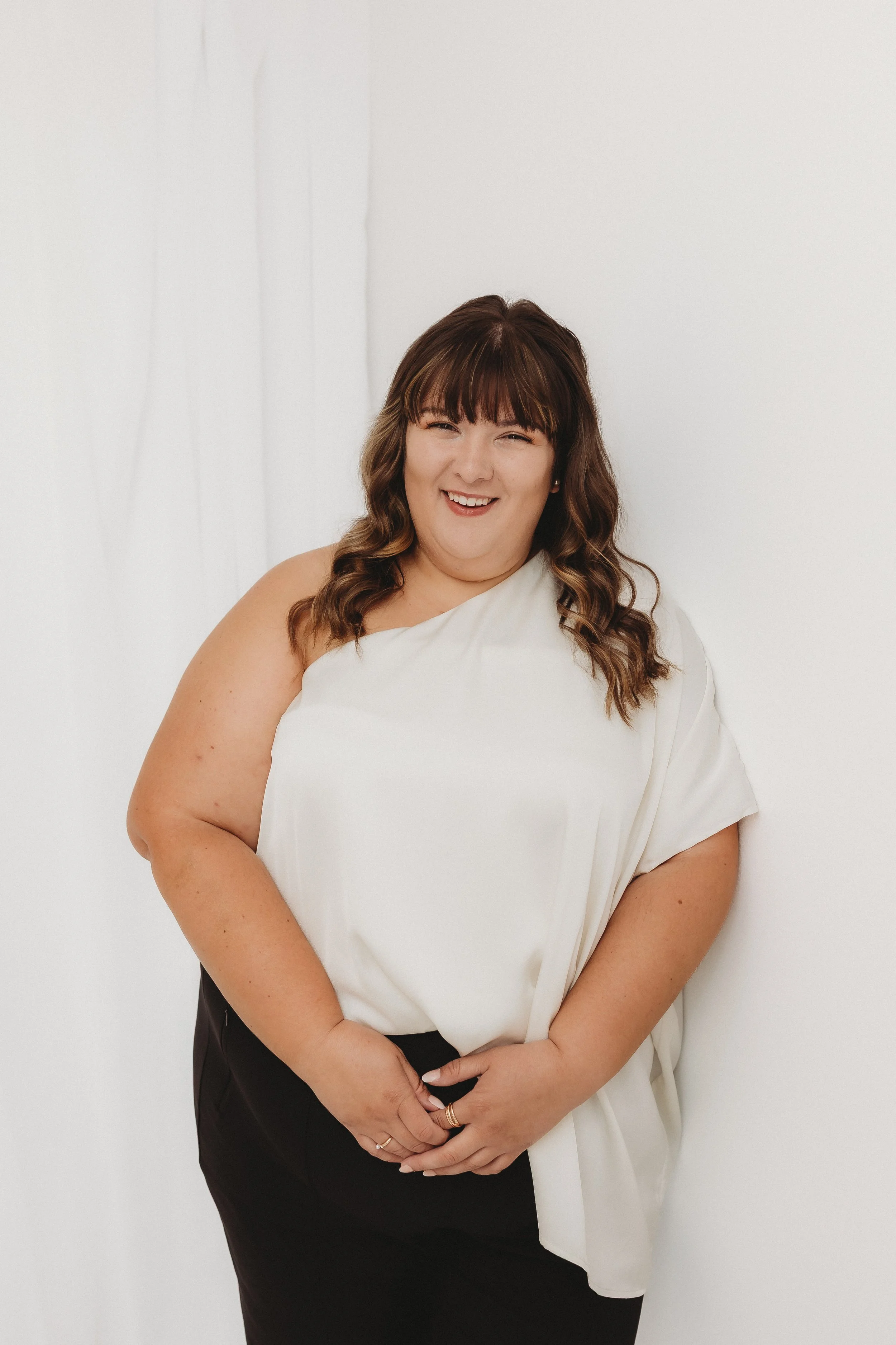 Systems expert, Bre Henderson, celebrating with gold confetti, holding a champagne glass, smiling, against a plain white wall.