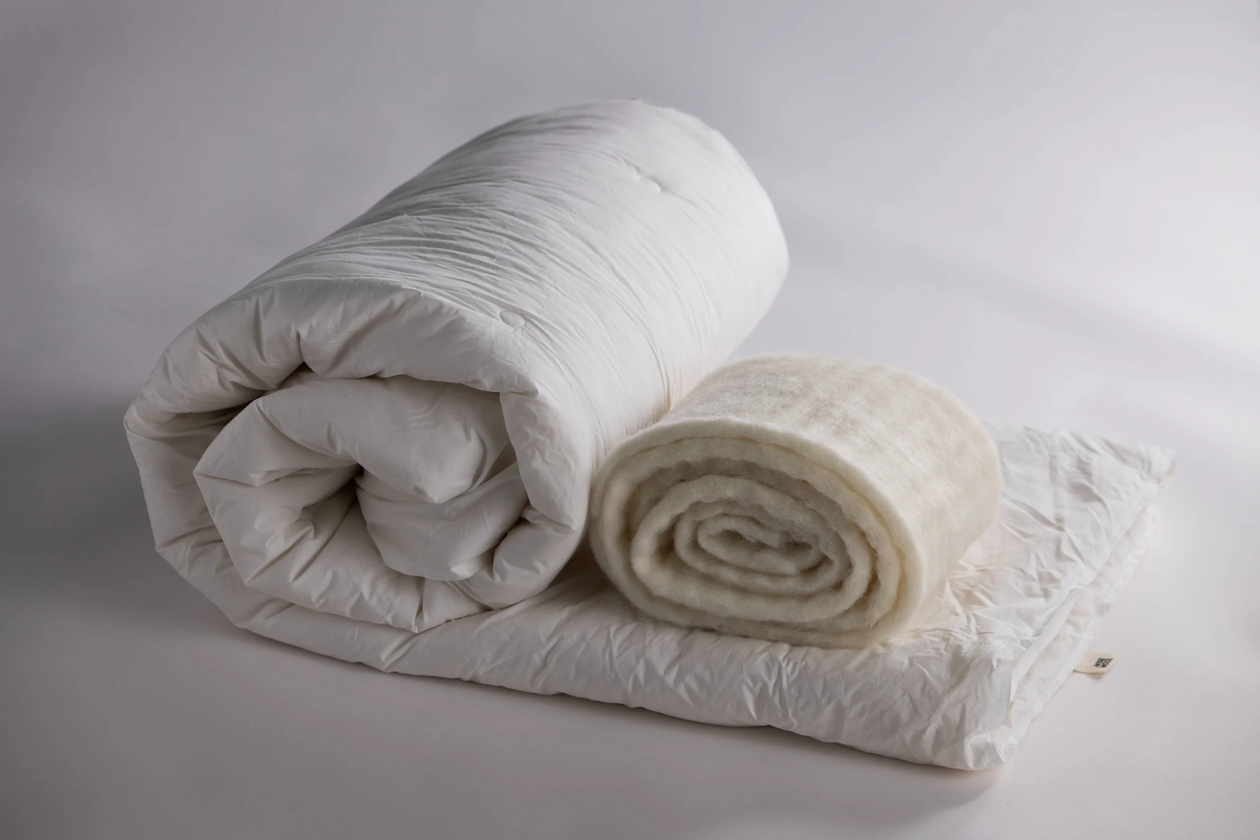 A mental rolled-up white blanket inside a paired-down white pillow.