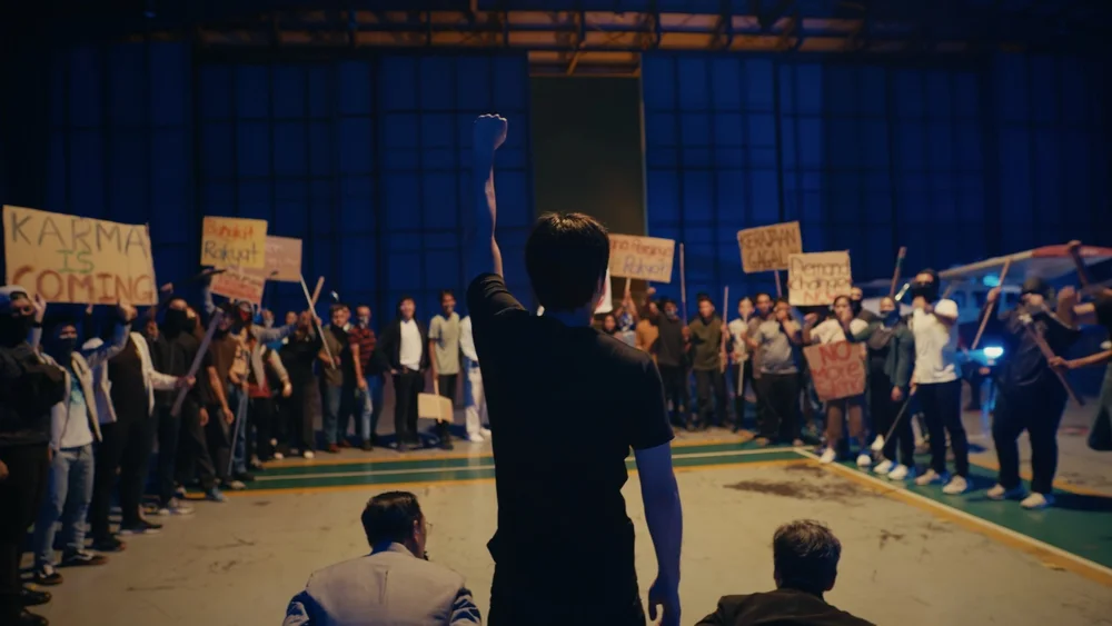 Wide view of a crowd in a blue-lit warehouse, from One Cent Thief Episode 8