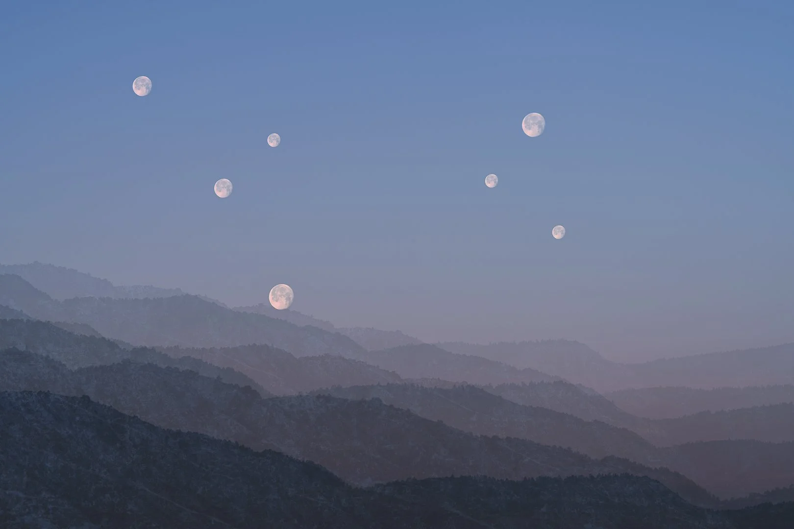 Multiple moons over a mountainous landscape at dawn.