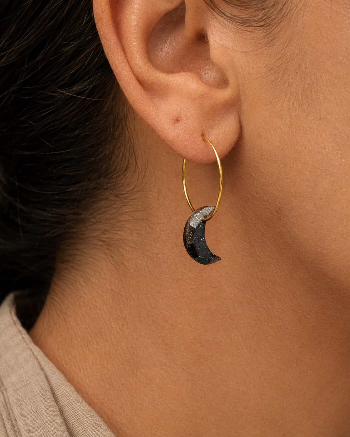 Close-up of Galaxy moon hoop earring by Atelier Cayelle, featuring a dark recycled coffee moon on a nickel-free gold hoop.