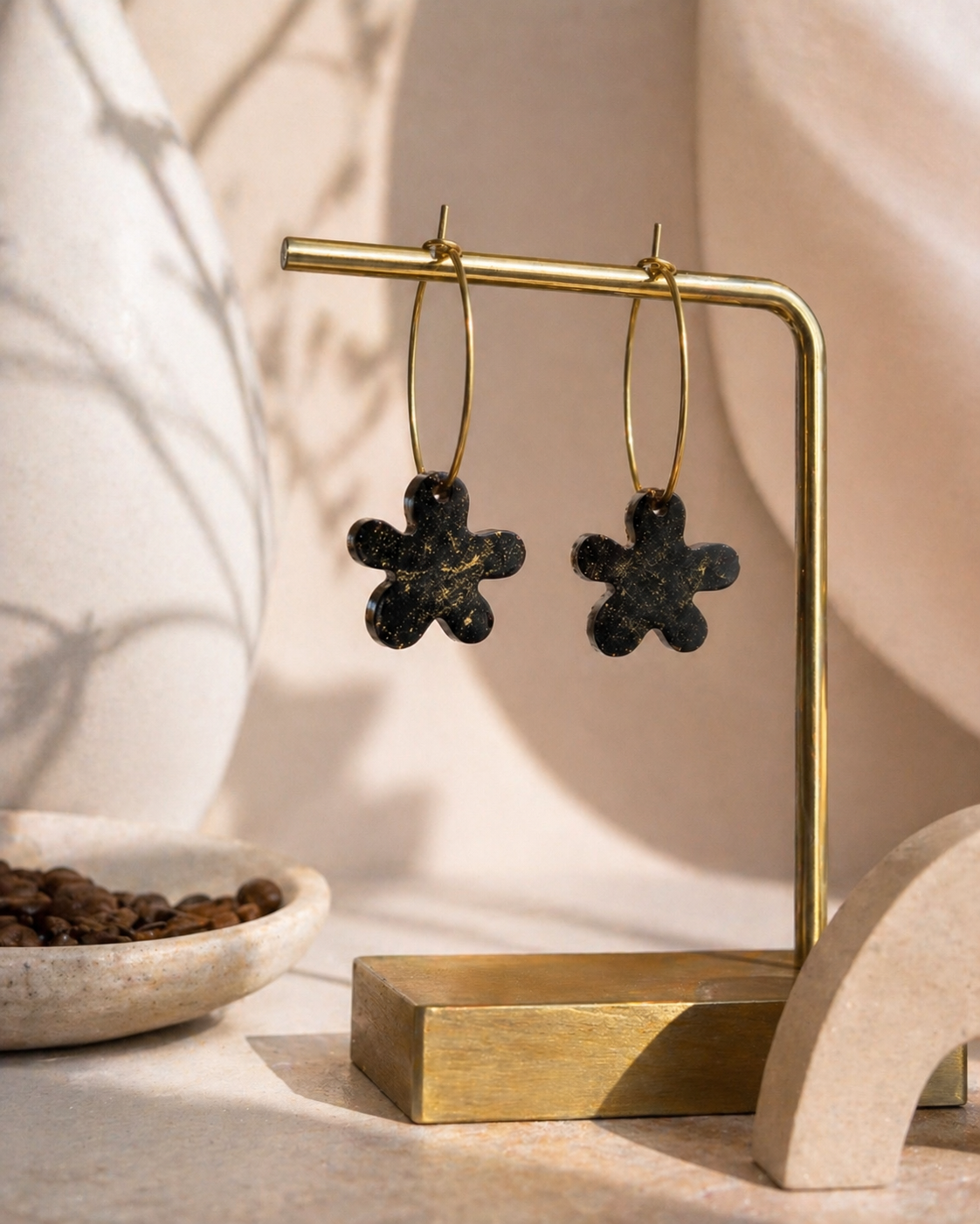 Black flower hoop earrings made from recycled coffee grounds displayed on a gold jewellery stand, handmade in Melbourne