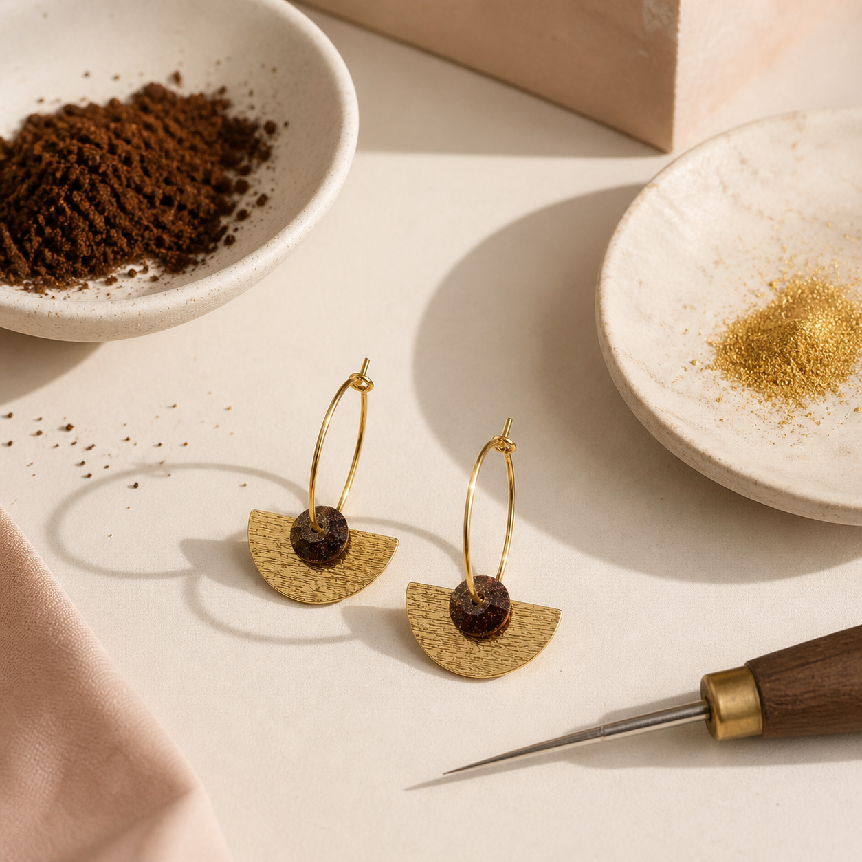 Recycled coffee gem hoop earrings with gold-plated semi-circle on neutral surface with coffee grounds and jewellery tools