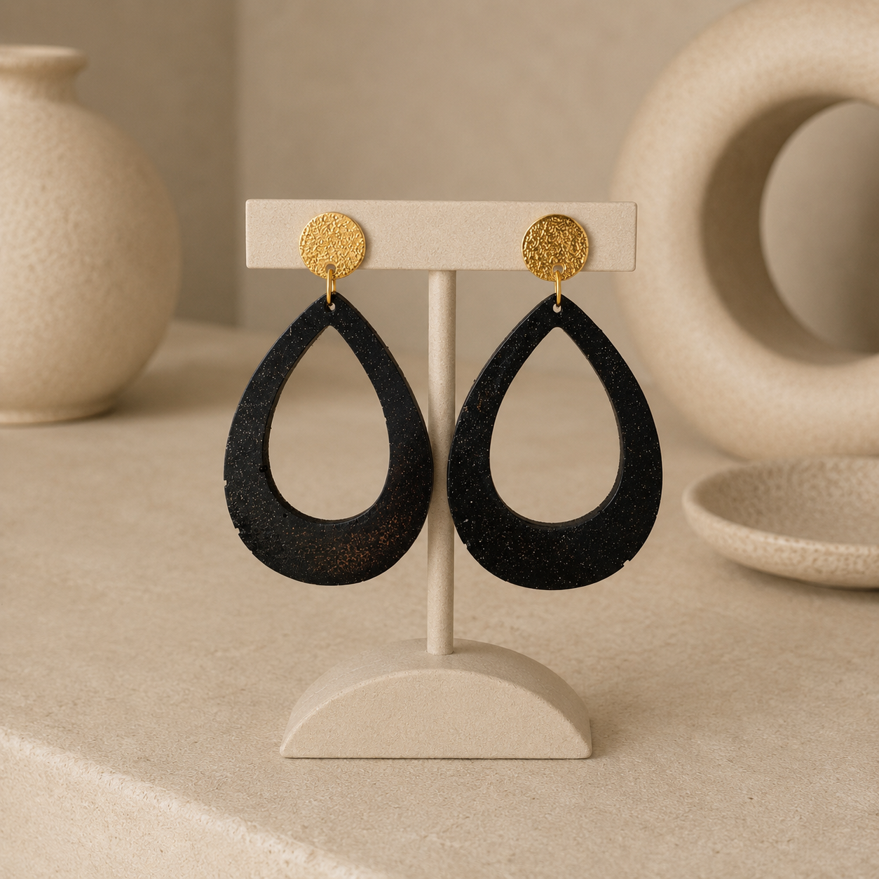 Lola recycled coffee teardrop earrings by Atelier Cayelle on a cream jewellery stand with textured gold-tone studs.