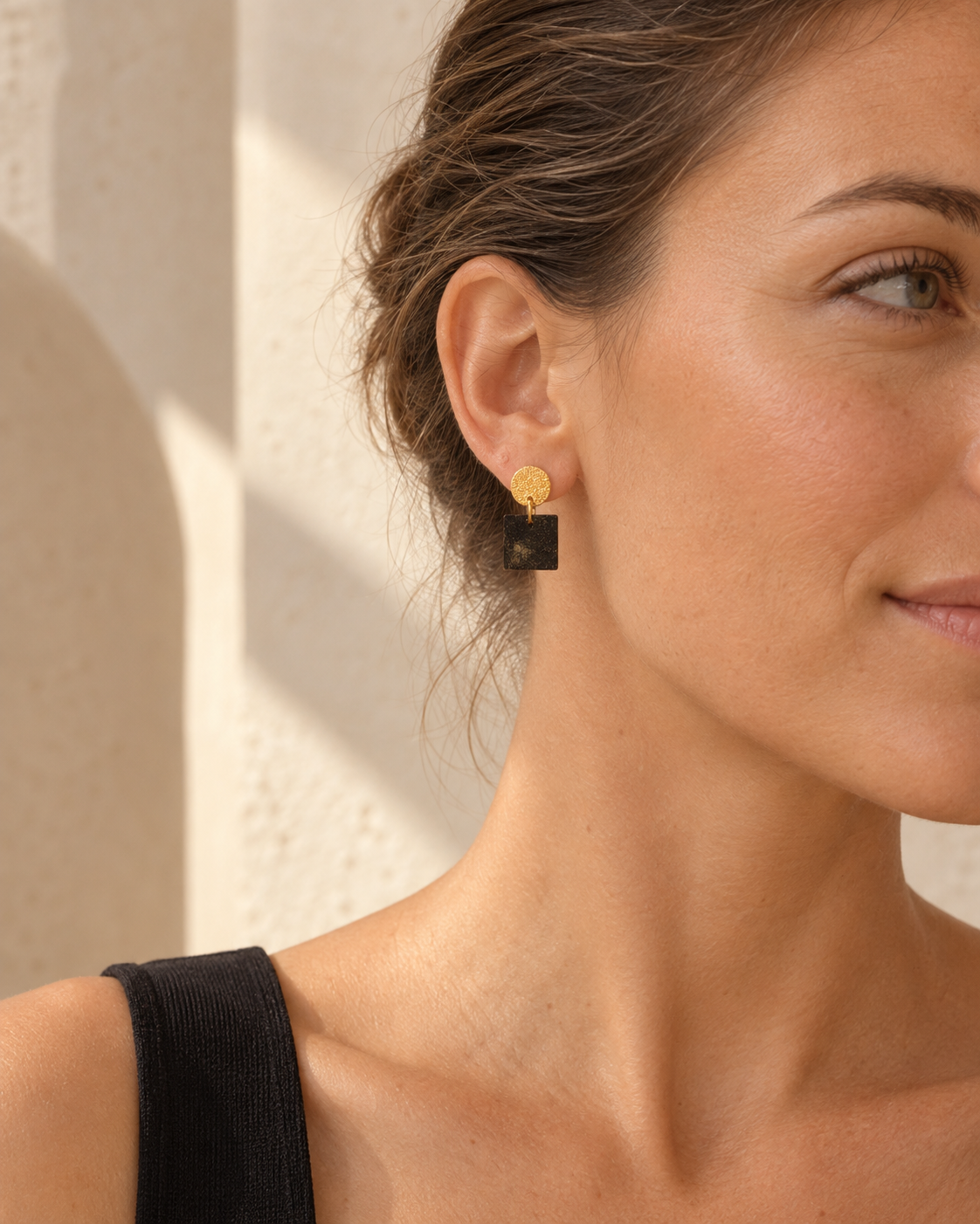 Close-up of Marie coffee-stone square earrings worn on the ear, showing the textured gold stud, espresso-brown square and scale.