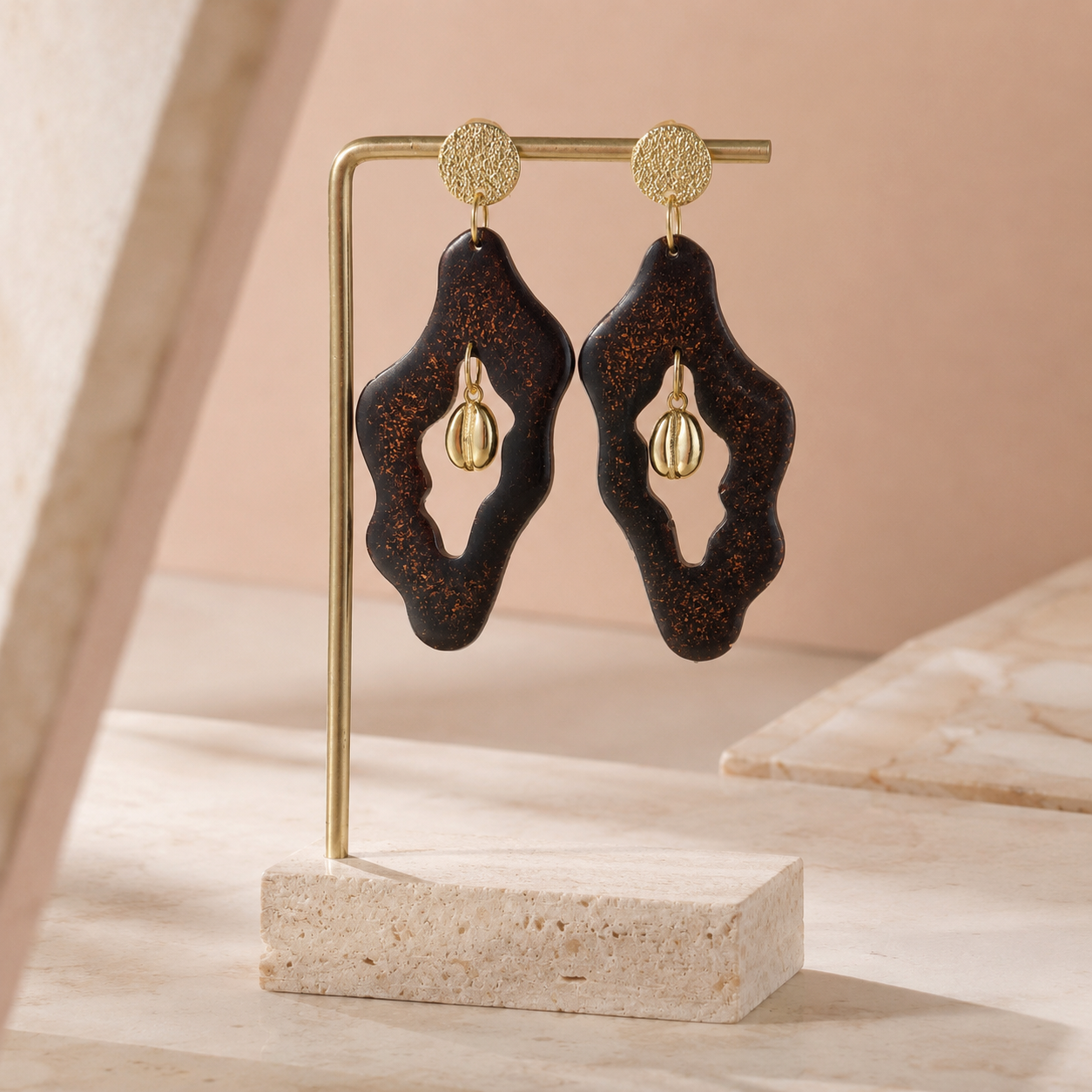 Oh My Bean handmade coffee ground earrings laid flat on textured stone, with real gold powder and gold-plated coffee bean centres.