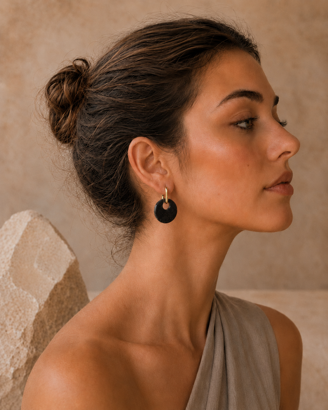 Side view of a model wearing Lou earrings, featuring removable black recycled coffee discs and 18K gold-plated findings.