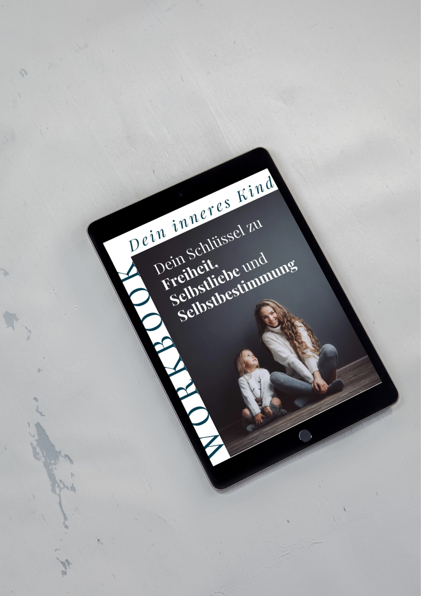 Tablet mit Buchcover, das eine Frau und ein Mädchen zeigt, die auf dem Boden sitzen, während das Buch Thema Selbstliebe und Selbstbestimmung behandelt.