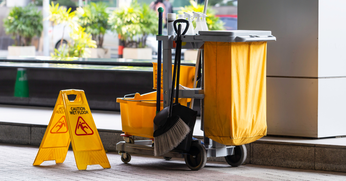 janitor's cart with brooms and safety signs