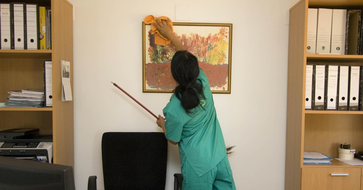 woman dusting a picture frame on the wall