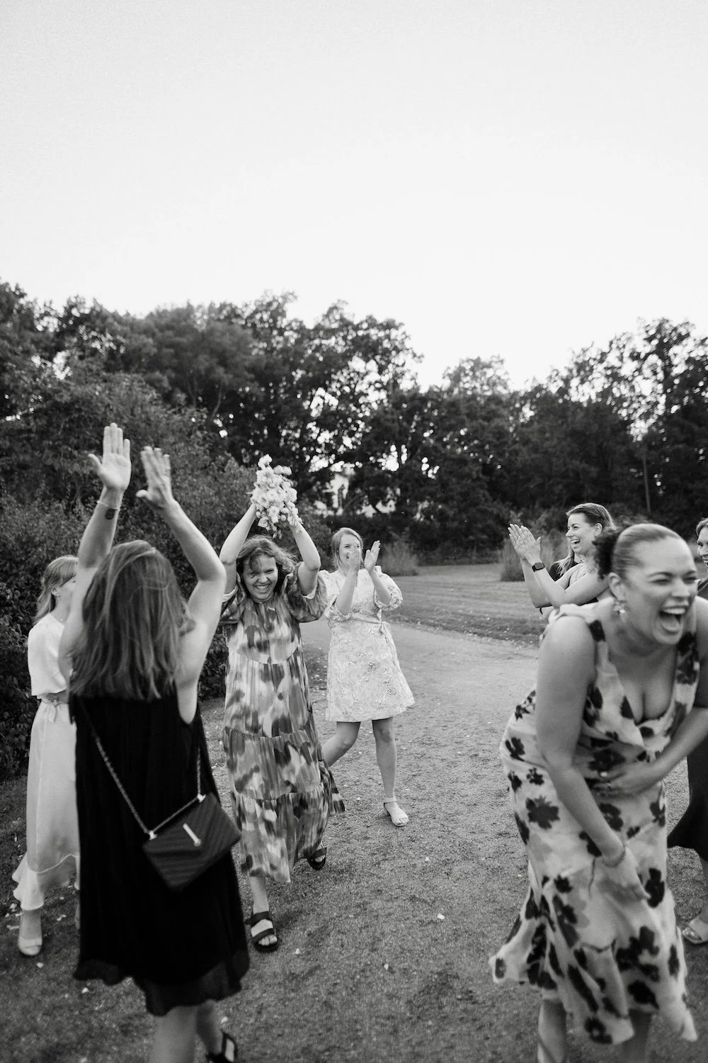 Vihreiden puiden takana on pari säkkipimeää ihmistä. Puut on varjossa ja taivaalla on kirkas valo.