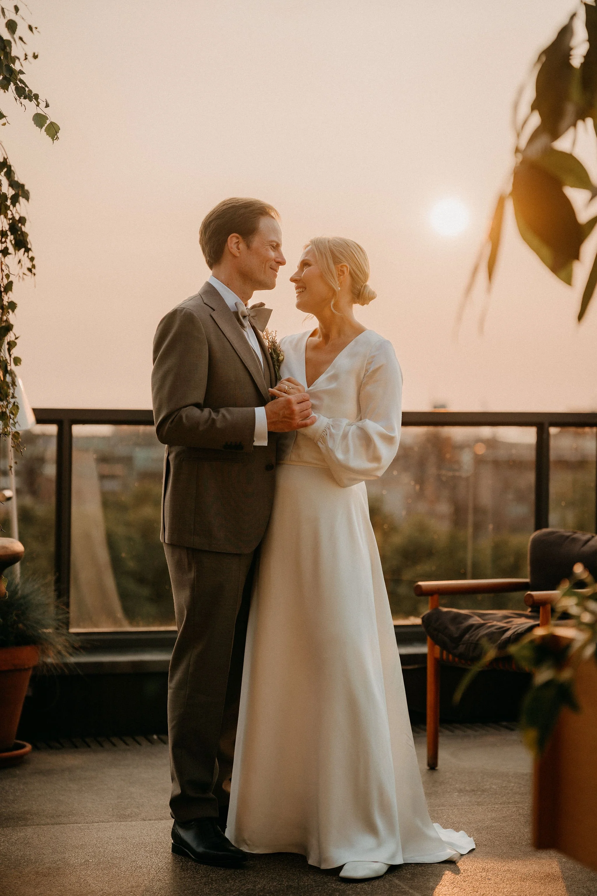 Pariskunta tanssii avioliiton vihkimisen jälkeen auringonlaskun aikaan katolla, taustalla näkyy kaupunkimaisema.