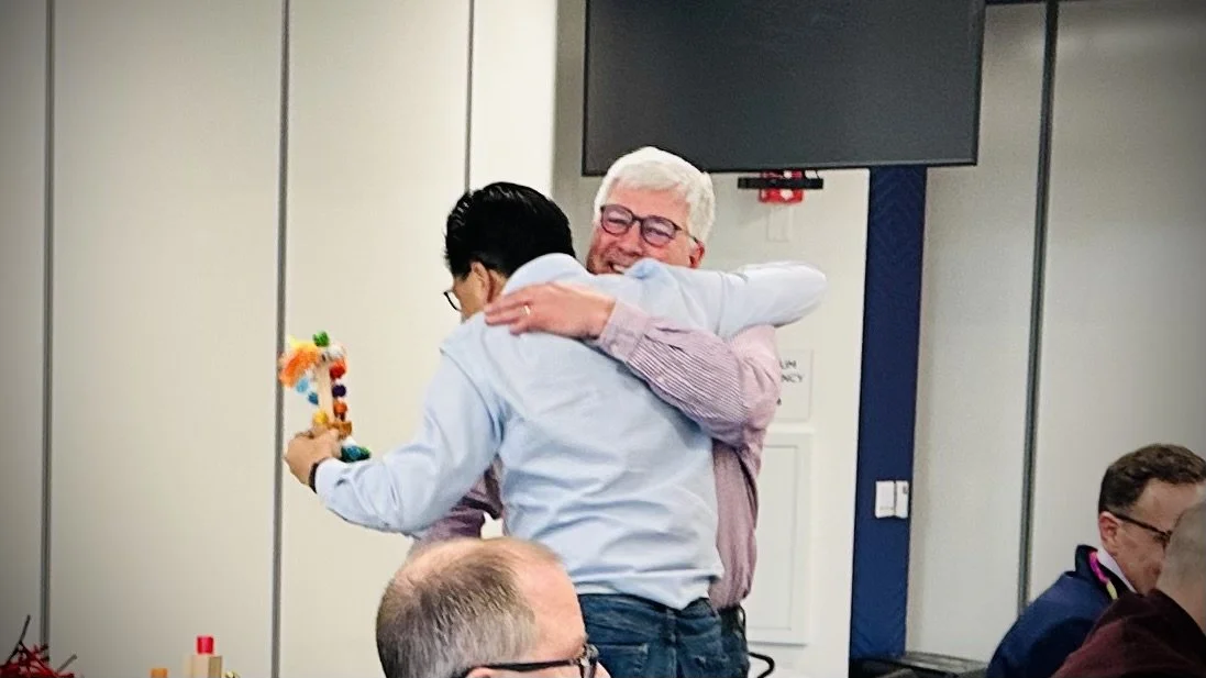 Teammates hugging after presenting their combined superhero character during a Make Believe Works creative team building activity