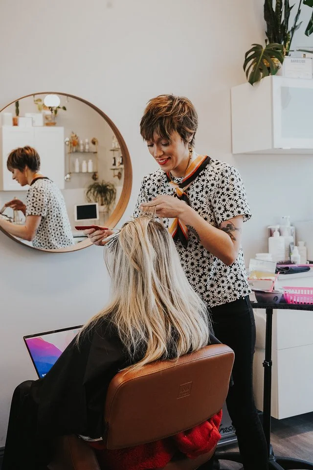 hair stylist cutting clients hair in her beauty rental suite