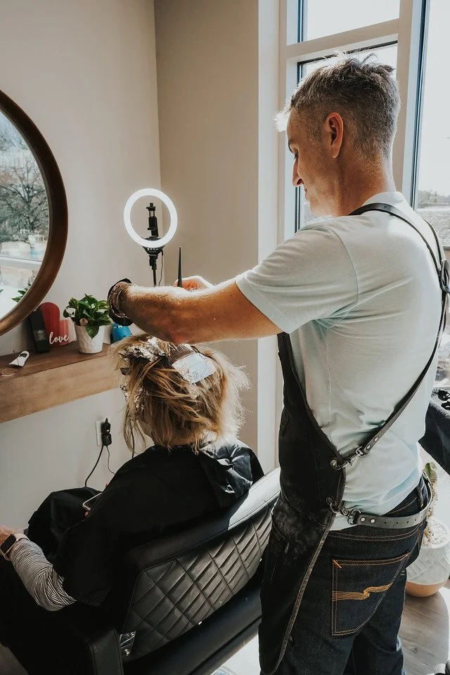 hair stylist coloring his client hair in his beauty rental suite