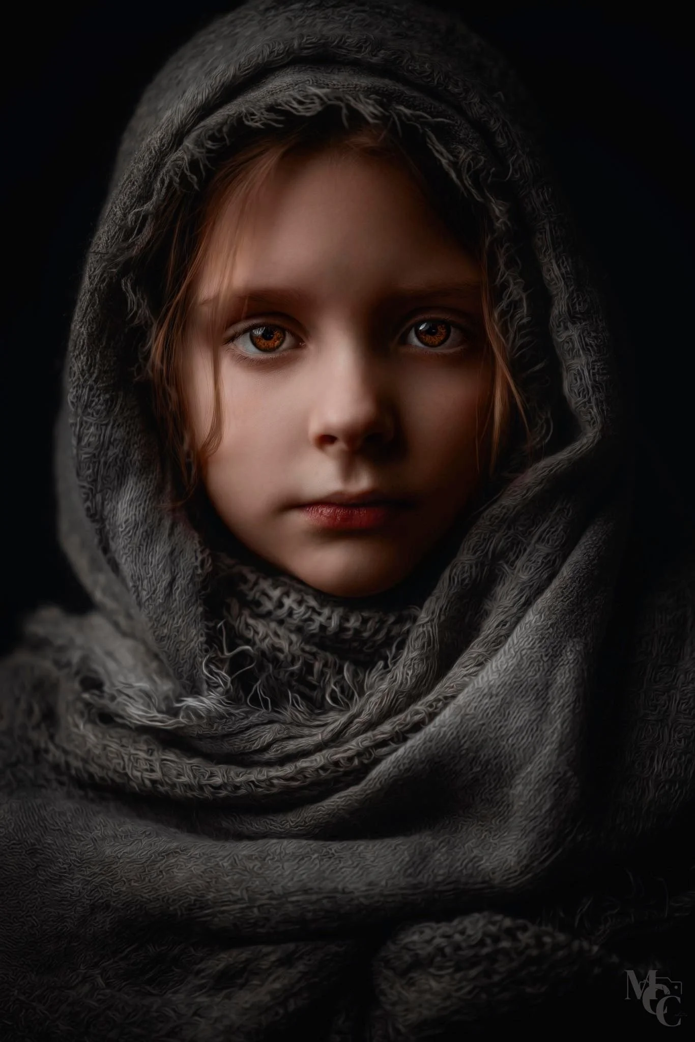 Close-up portrait of a young girl with brown hair and brown eyes, wrapped in a dark, textured scarf with a hood, against a black background.