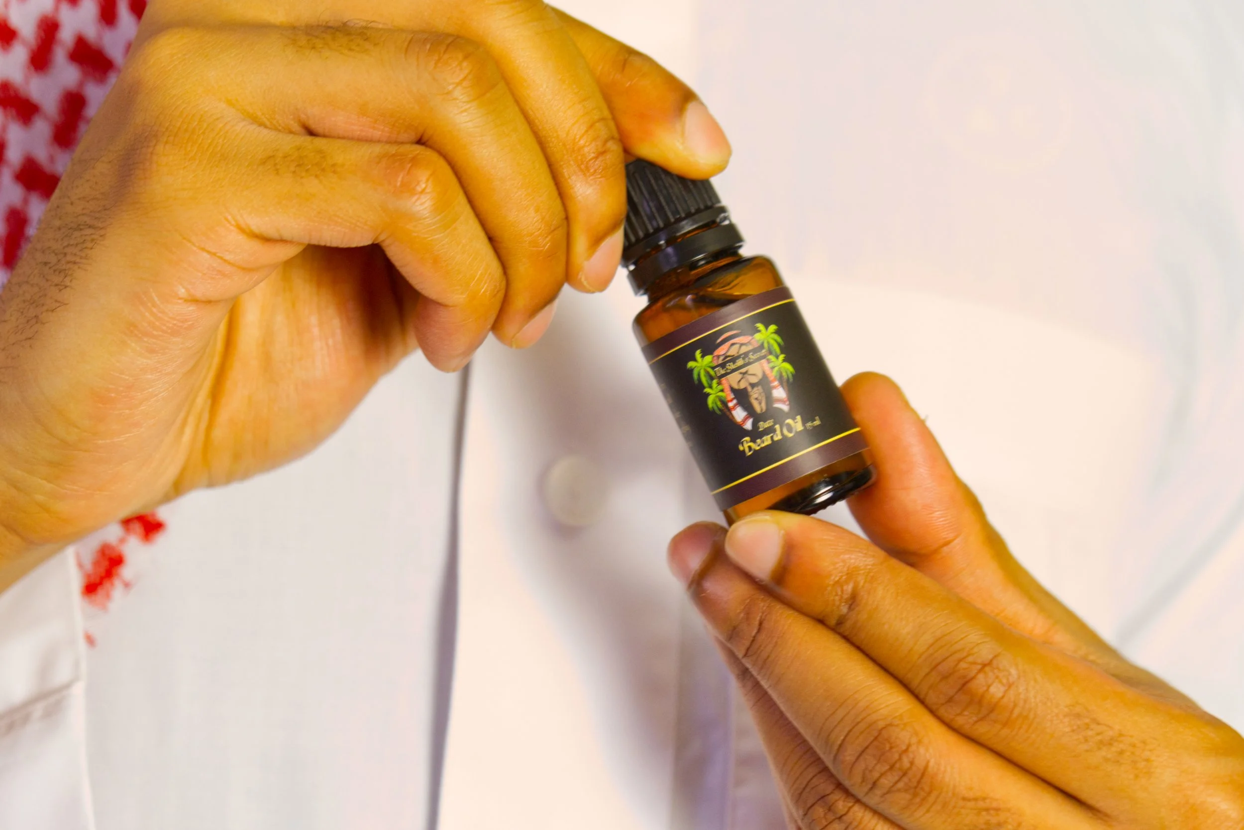 A Sheikh holding a small bottle labeled 'The Sheikhs's Secret Beard Oil - Date Palm'
