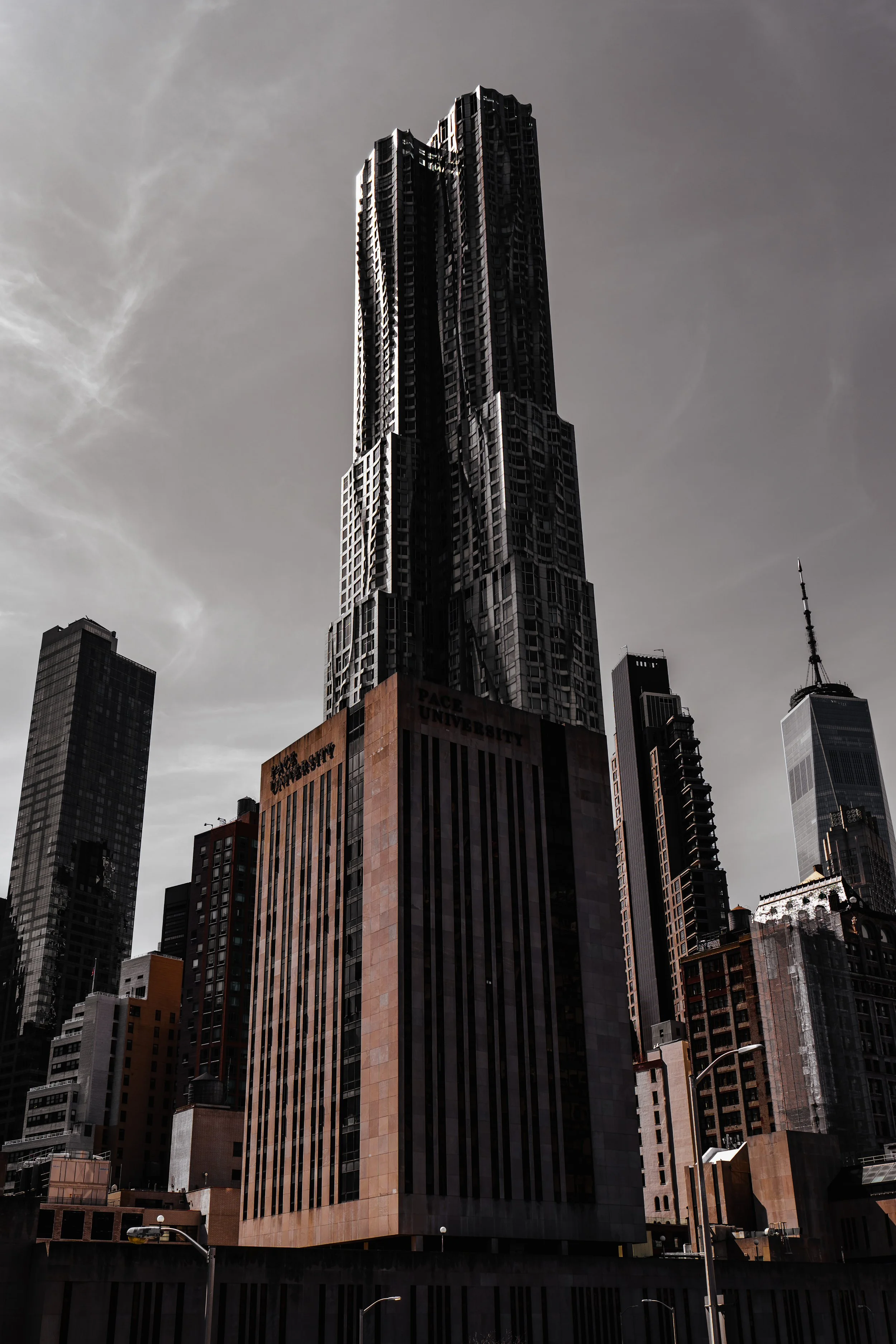 Skyscrapers in a city skyline with tall, modern buildings, including the distinct textured facade of a prominent tower, under an overcast sky.
