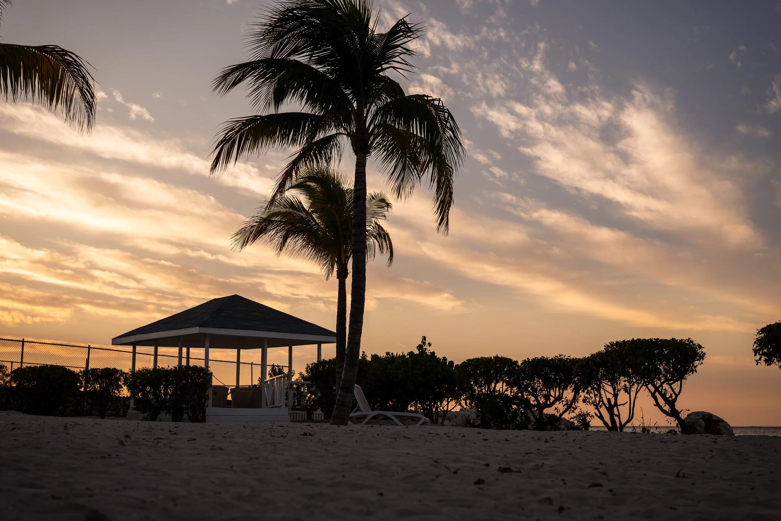 Beach gazebo with palm trees at sunset