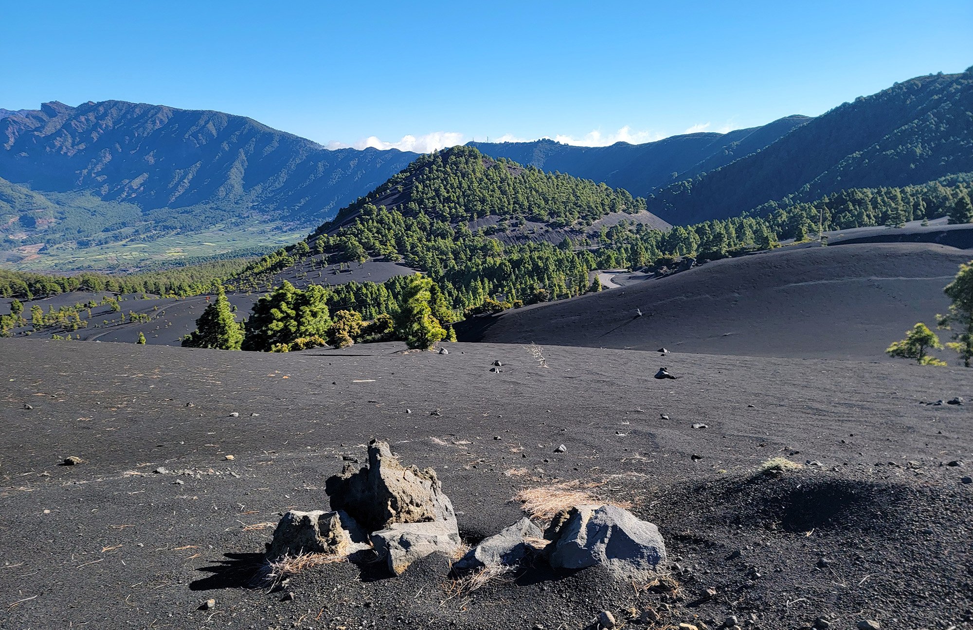 You rapidly exit the forest to keep climbing down along this crater filled with black sands.