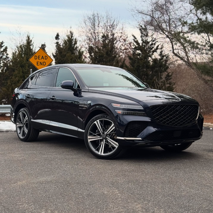 Dark blue Genesis GV80 luxury SUV with crest grille, quad LED headlights, chrome side molding, and two-tone multi-spoke wheels parked outdoors