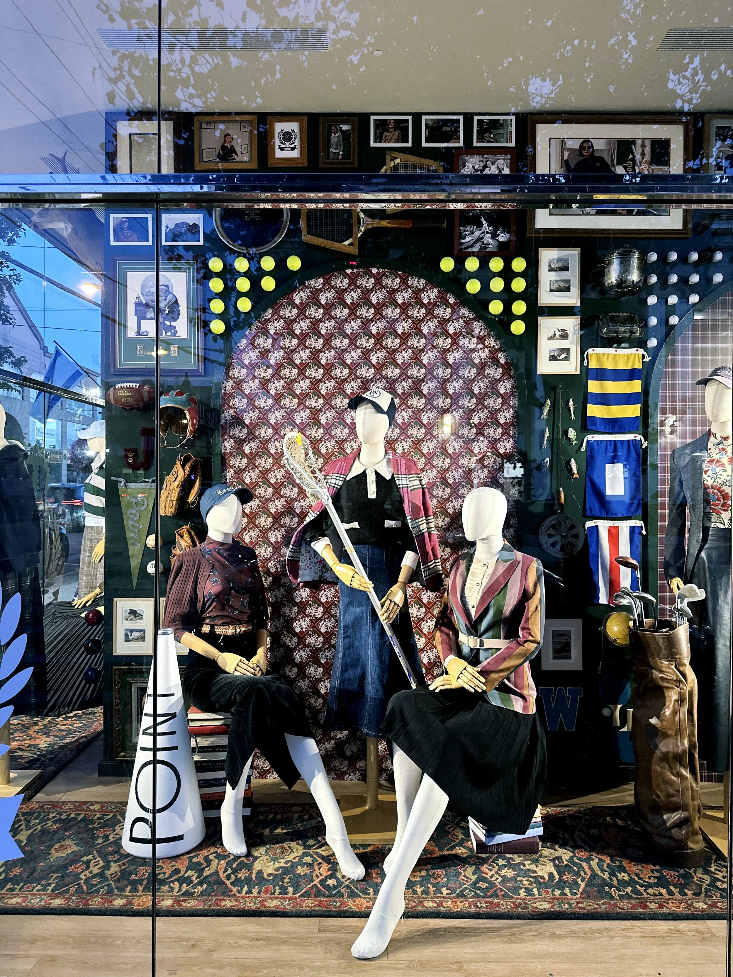 A group of mannequins in a study/den set in a collegiate themed for a retail window display