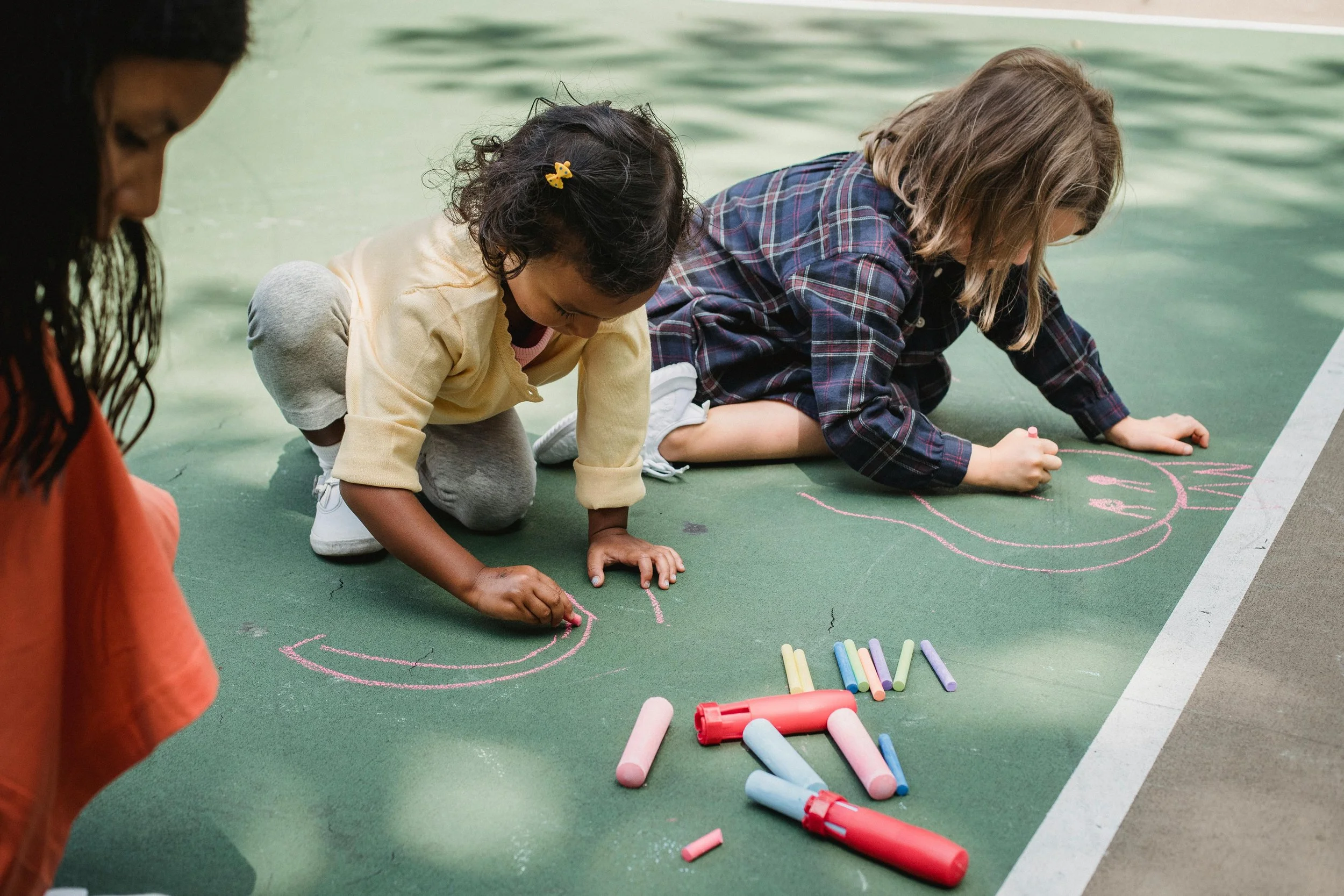 Two kids chalking a sidewalk