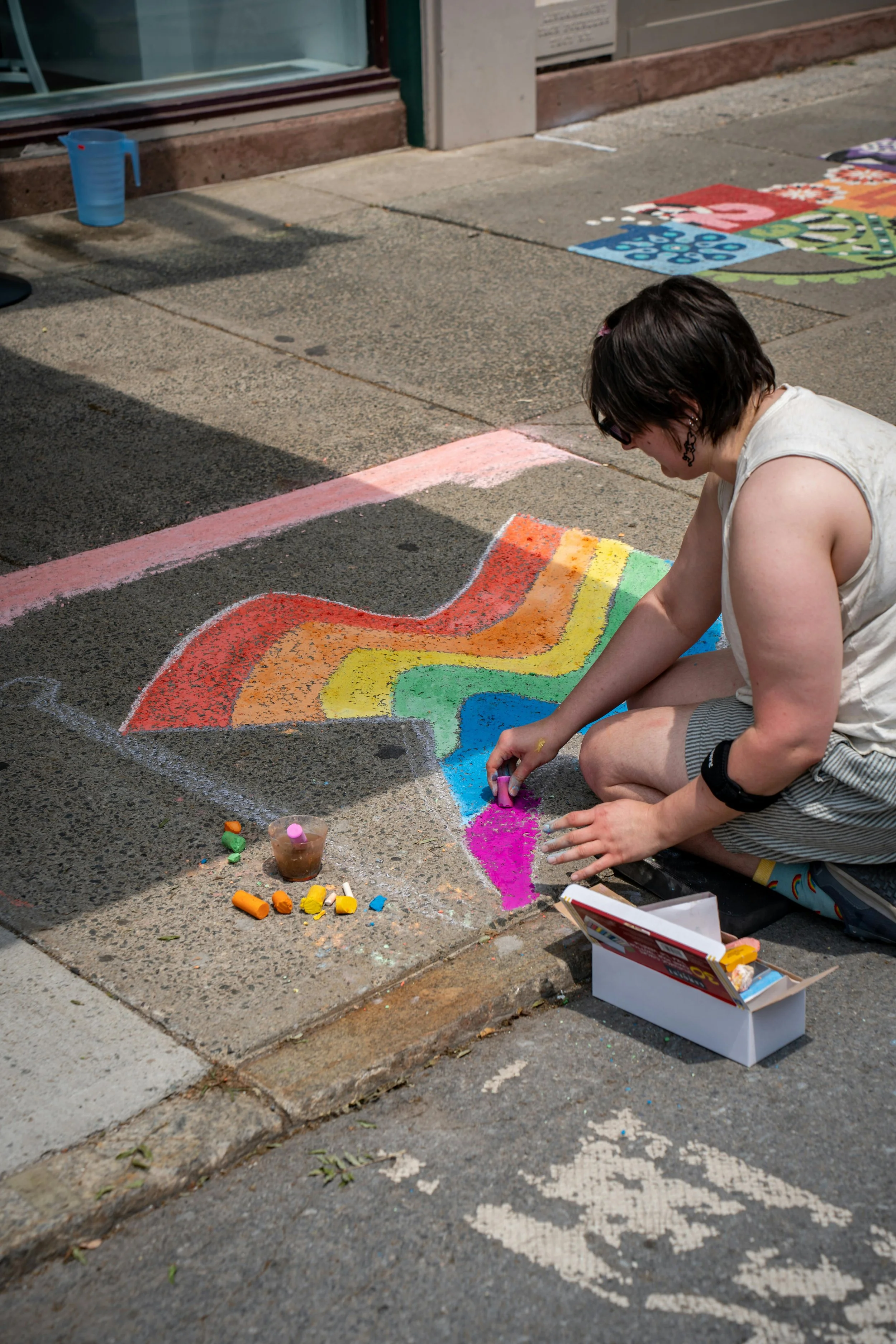 Chalking a sidewalk with a rainbow LGBTQ flag