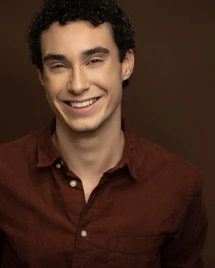 Person smiling wearing a brown shirt against a brown background.